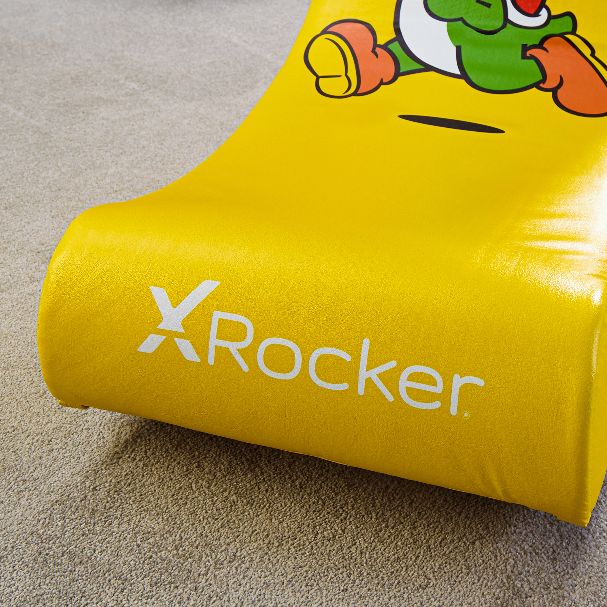 Een gele X-Rocker stoel met een Yoshi-personage erop, op een tapijt.