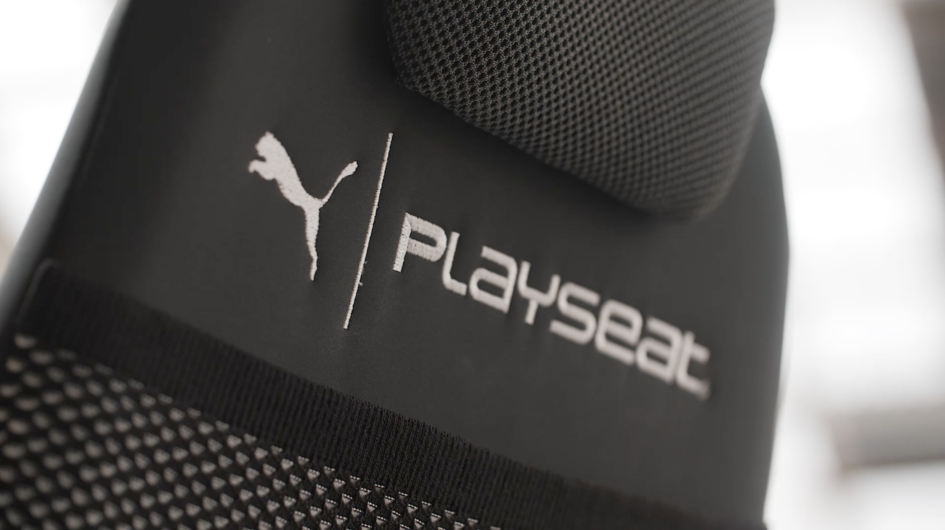 Puma-Logo und Playseat-Schriftzug auf einem schwarzen Sitz.