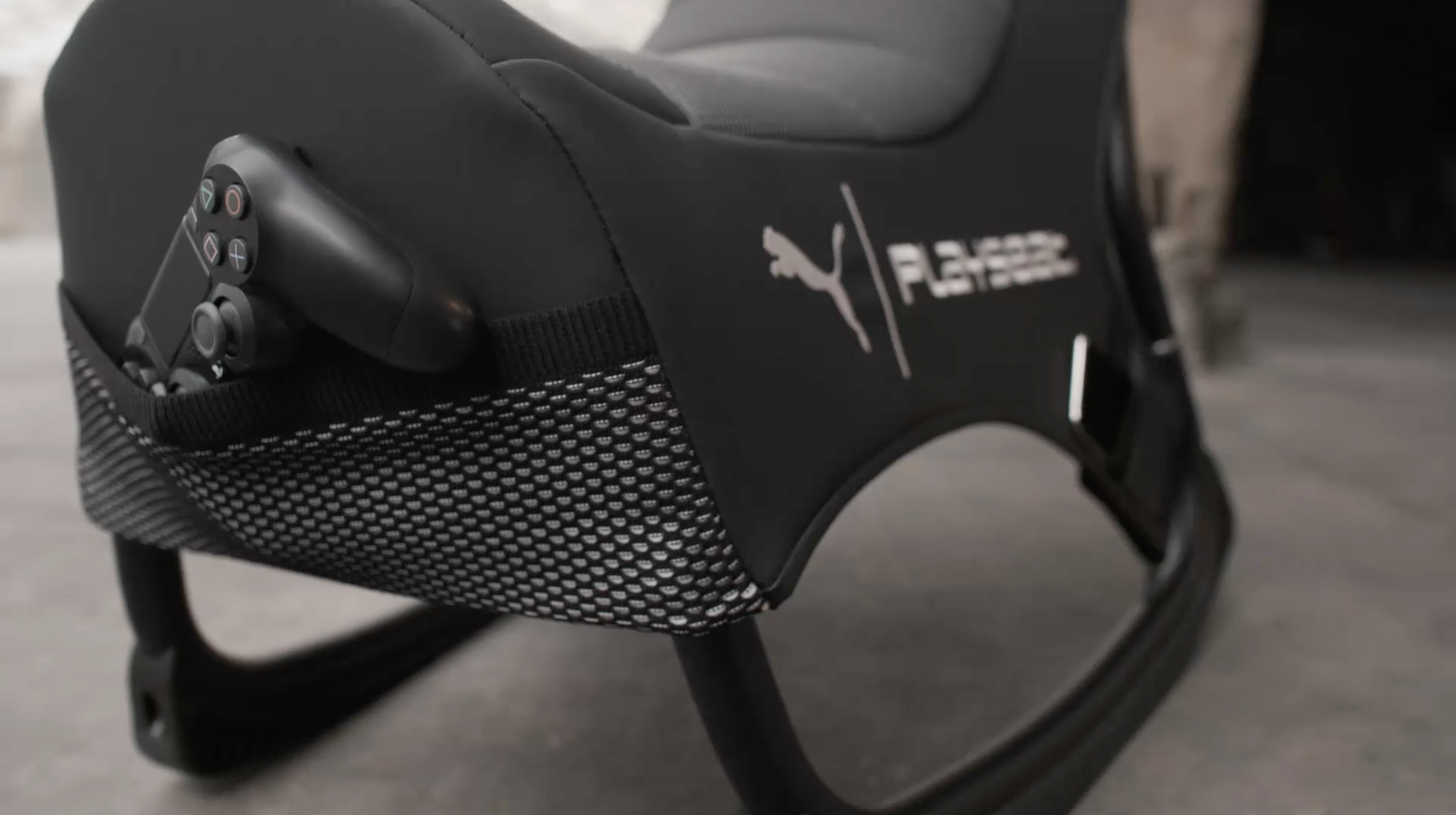 Schwarzer Gaming-Stuhl mit einem Controller in einer Netzseitentasche.