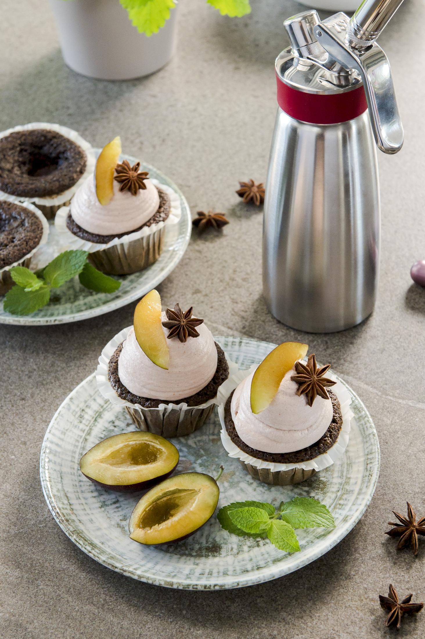 Schokoladenmuffins mit rosa Creme, Pflaumenstücken und Sternanis.