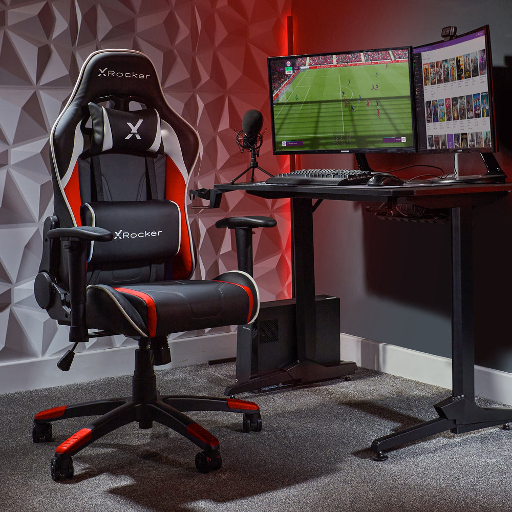 Gaming-Setup mit X-Rocker-Stuhl, zwei Monitoren mit Spielen und einem Mikrofon.