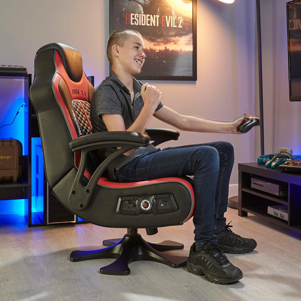 Ein Junge spielt in einem Gaming-Stuhl mit einem Controller. Resident Evil 2 Poster.