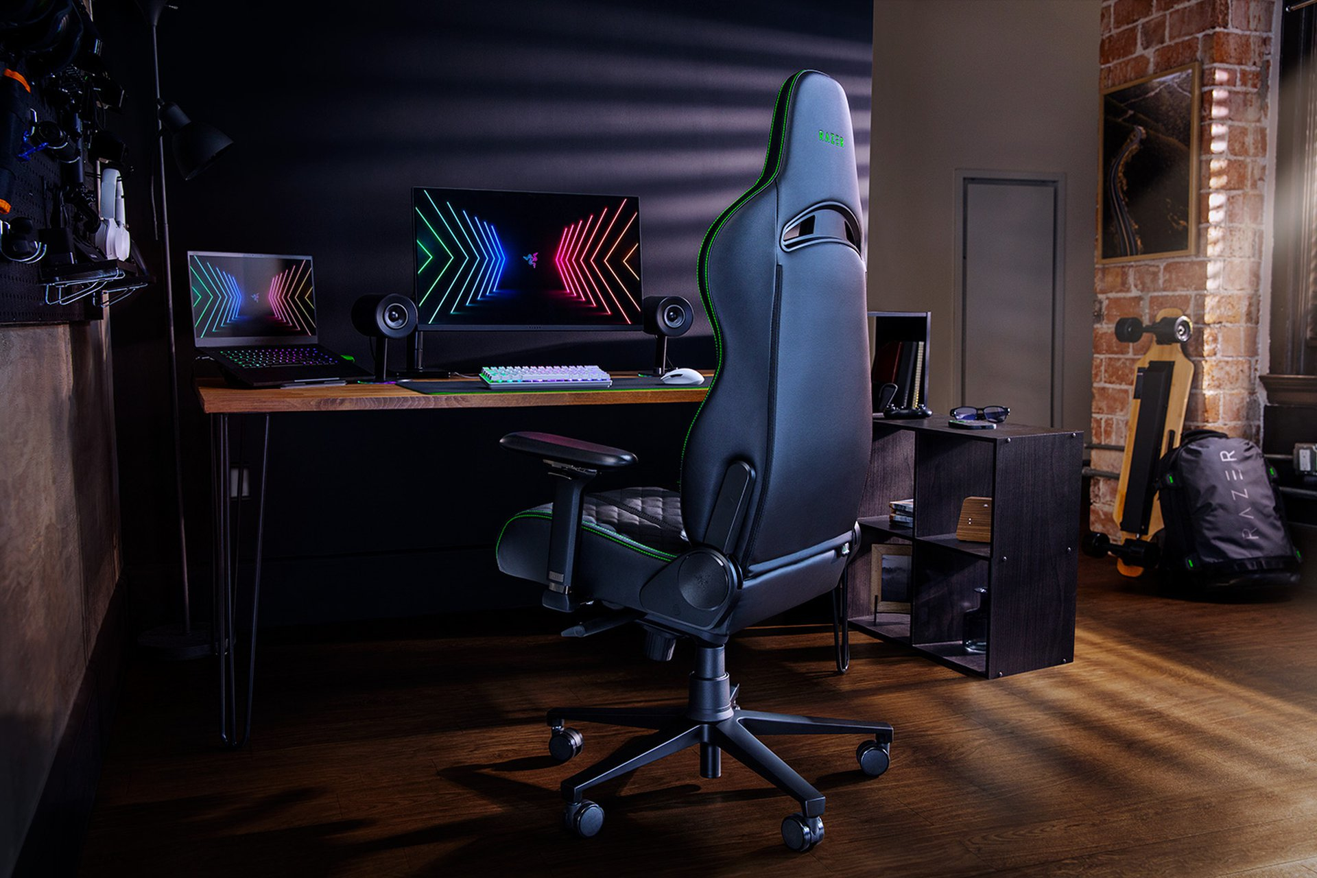 Ein Gaming-Setup mit schwarzem Razer-Stuhl, Schreibtisch, Laptop und Monitor.