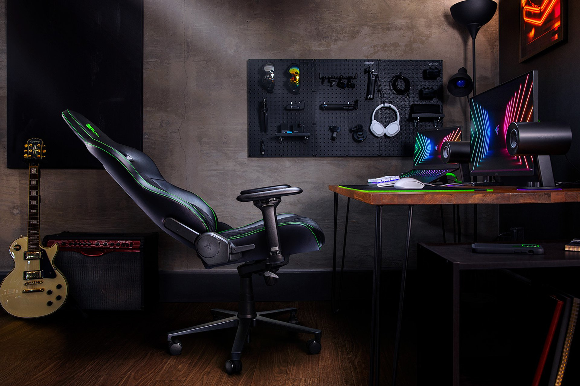 Ein Gaming-Stuhl, Gitarre, Verstärker und Computereinrichtung mit Monitoren und Kopfhörern.