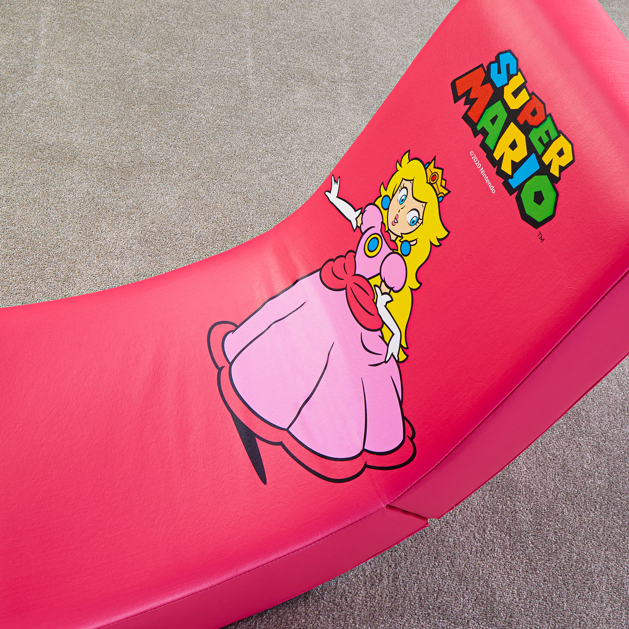 Prinses Peach en het Super Mario-logo op een rode zitting op tapijt.