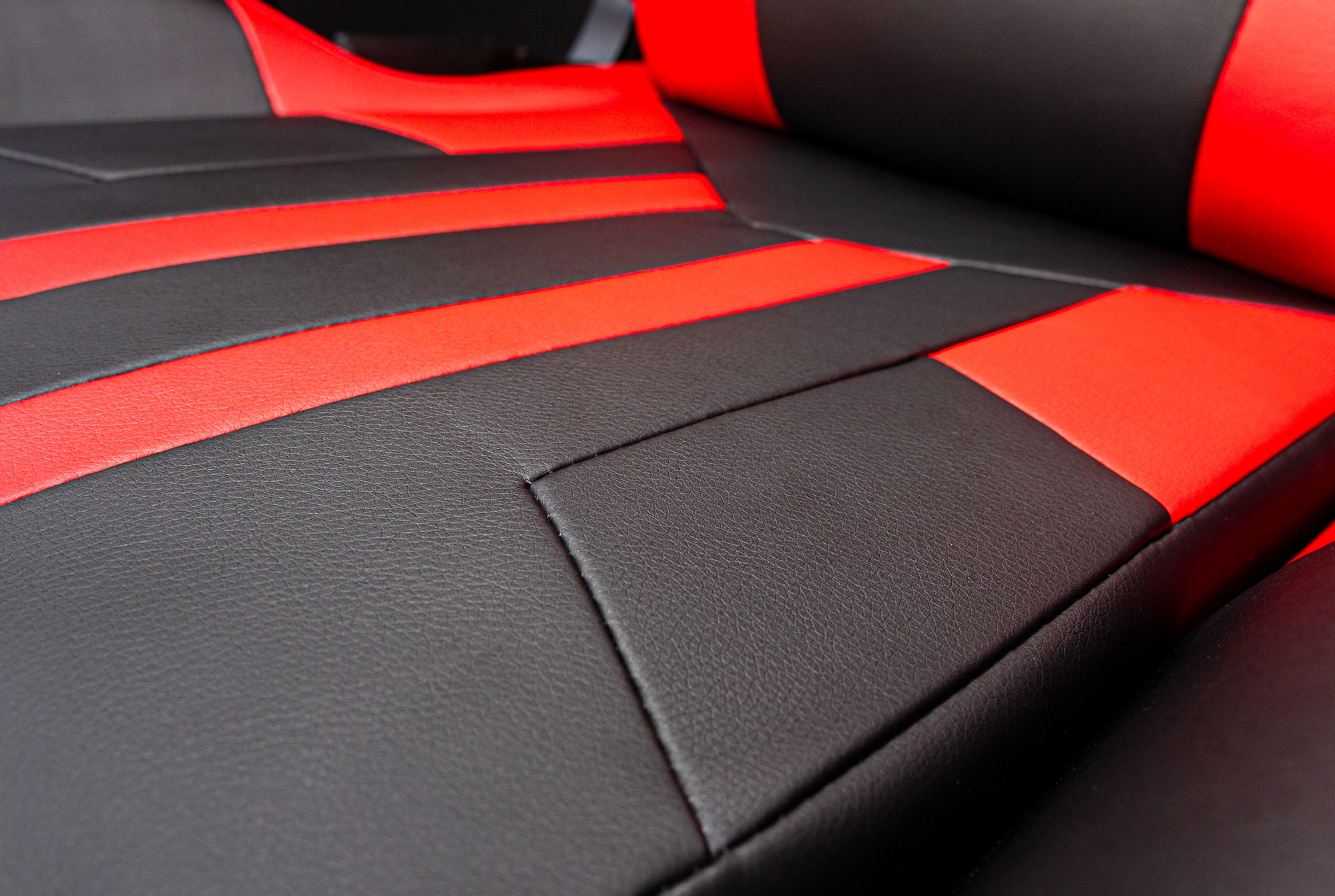 Asientos de cuero sintético negro y rojo con costuras.