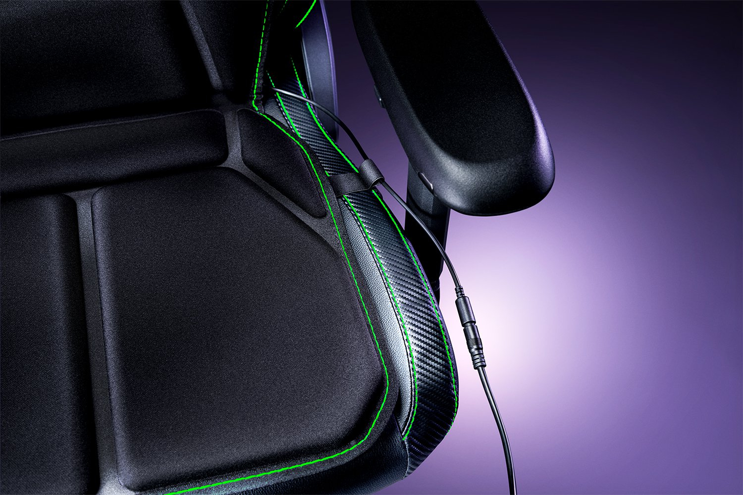 Nahaufnahme eines schwarzen Gaming-Stuhls mit grünen Nähten und schwarzem Kabel.