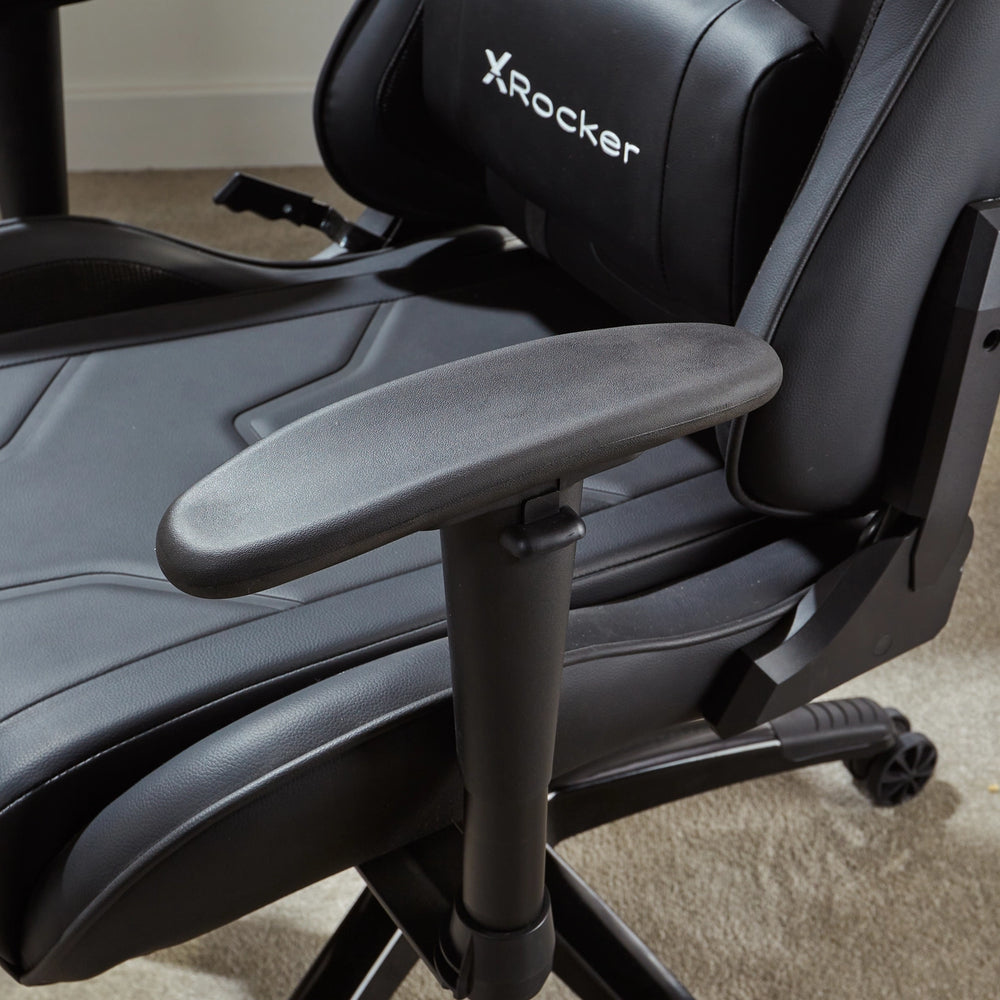 Ein schwarzer X-Rocker Gaming-Stuhl mit Armlehne und Rollen auf Teppichboden.