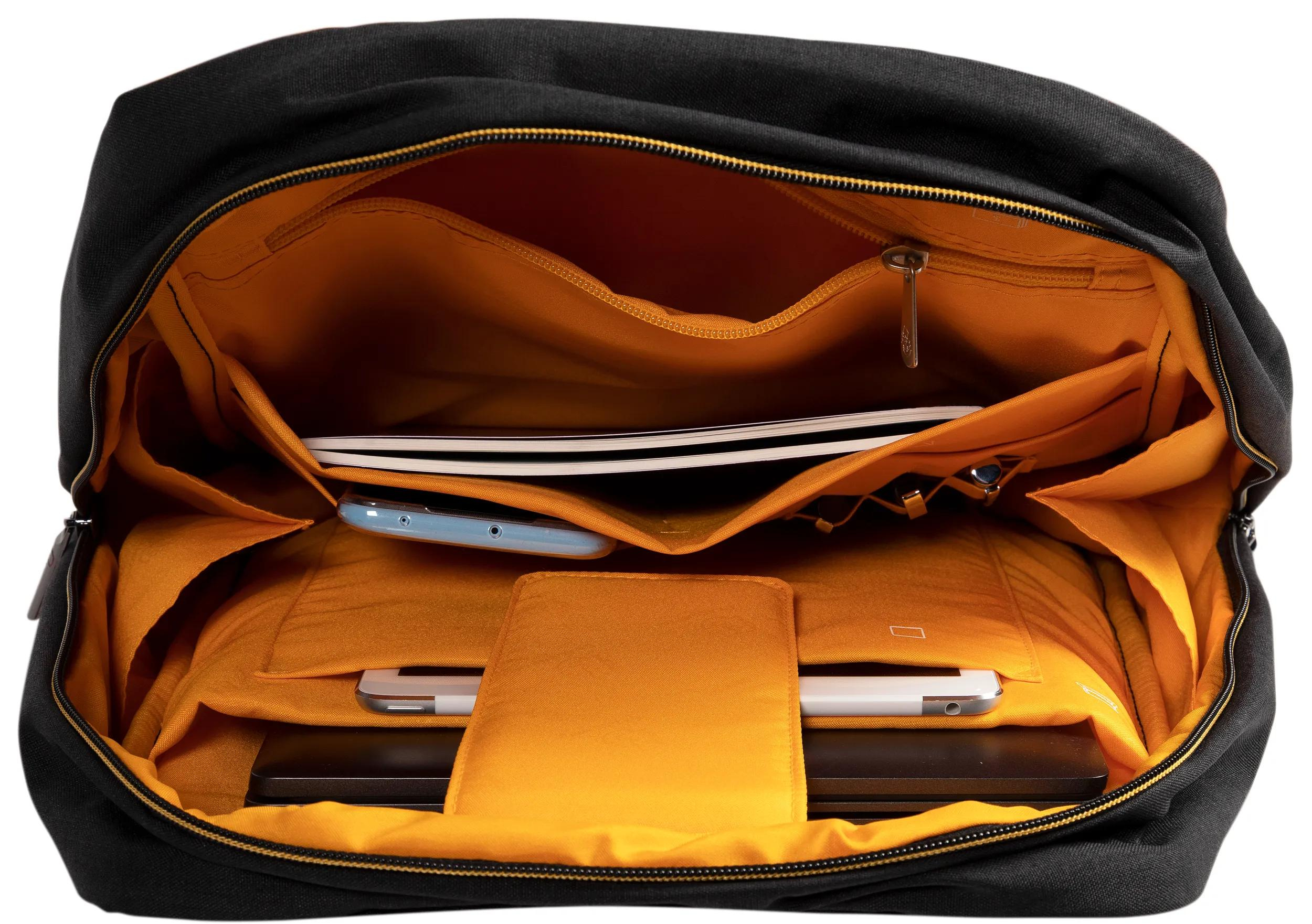 Interno zaino nero con fodera arancione, contiene telefono, laptop e taccuino.