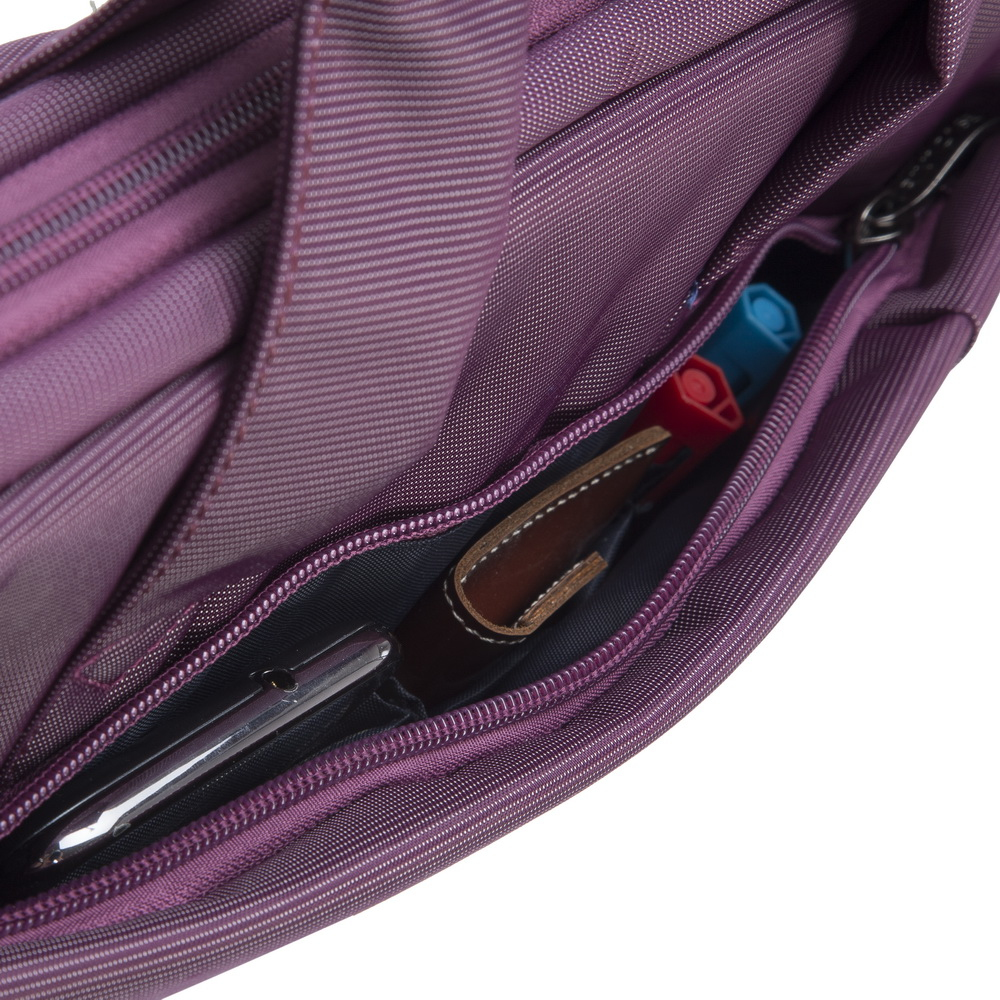 La tasca aperta di una borsa viola contiene una penna, un portafoglio e due pennarelli.