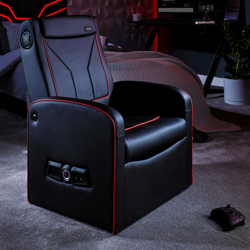 Schwarzer Gaming-Stuhl mit roter Zierleiste, Lautsprechern und Controller.