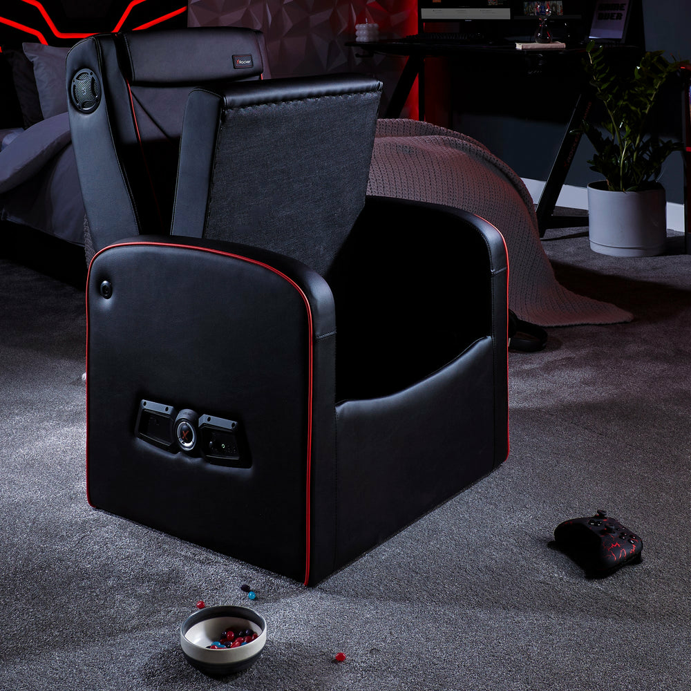 Schwarzer Gaming-Stuhl mit roten Akzenten, offen, mit Controller und Schüssel auf dem Teppich.