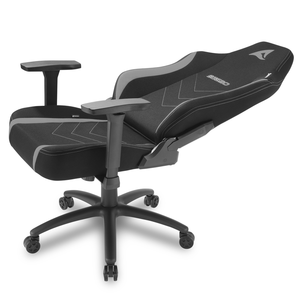 Una silla gamer negra con detalles grises y ruedas.