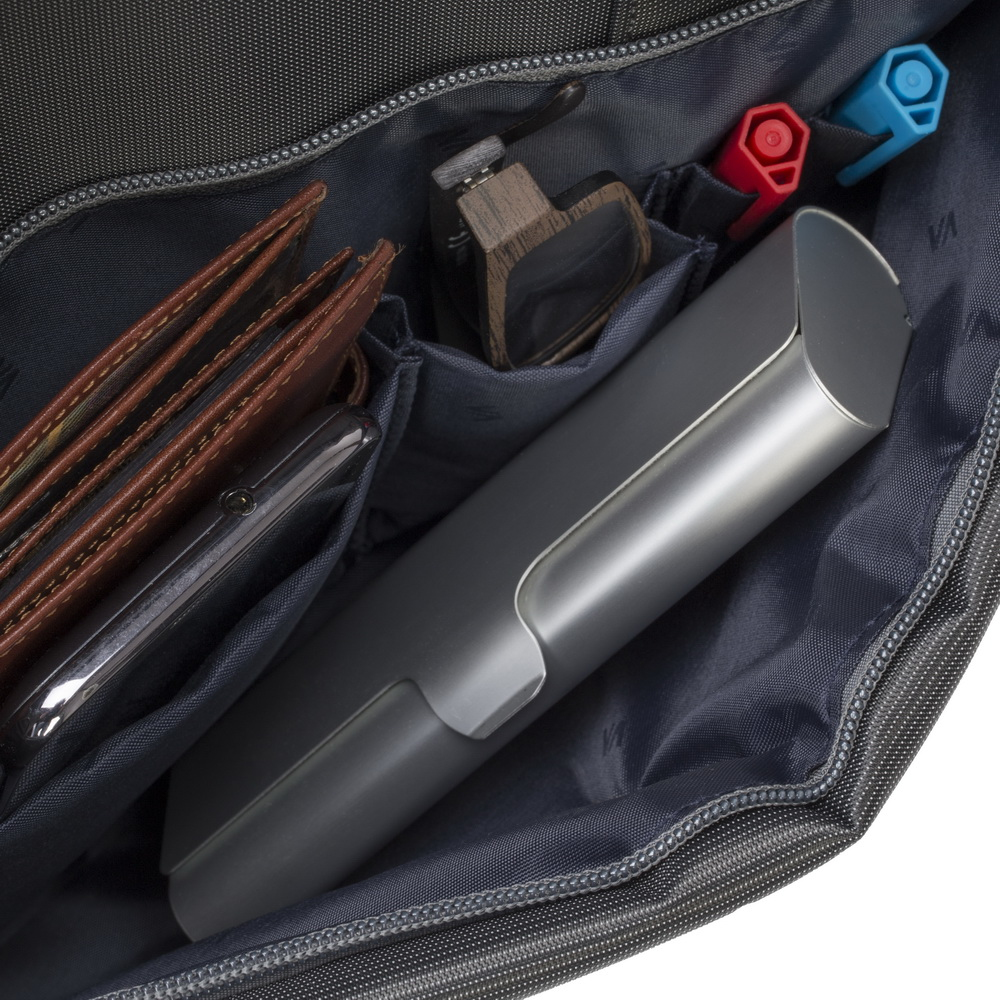 Gray bag interior with brown wallet, phone, glasses, red and blue pens.