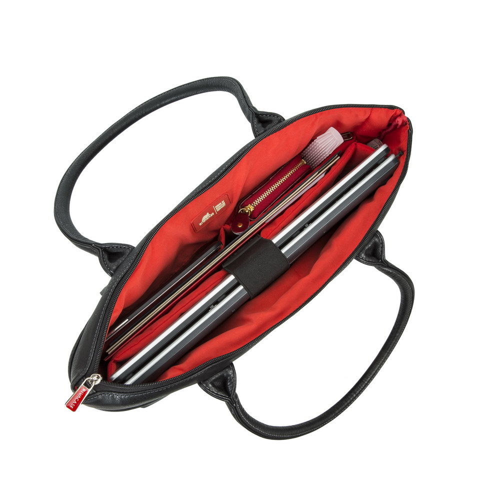 Borsa tote in pelle nera aperta, mostra un laptop, portafoglio rosso e altri oggetti all'interno con fodera rossa.