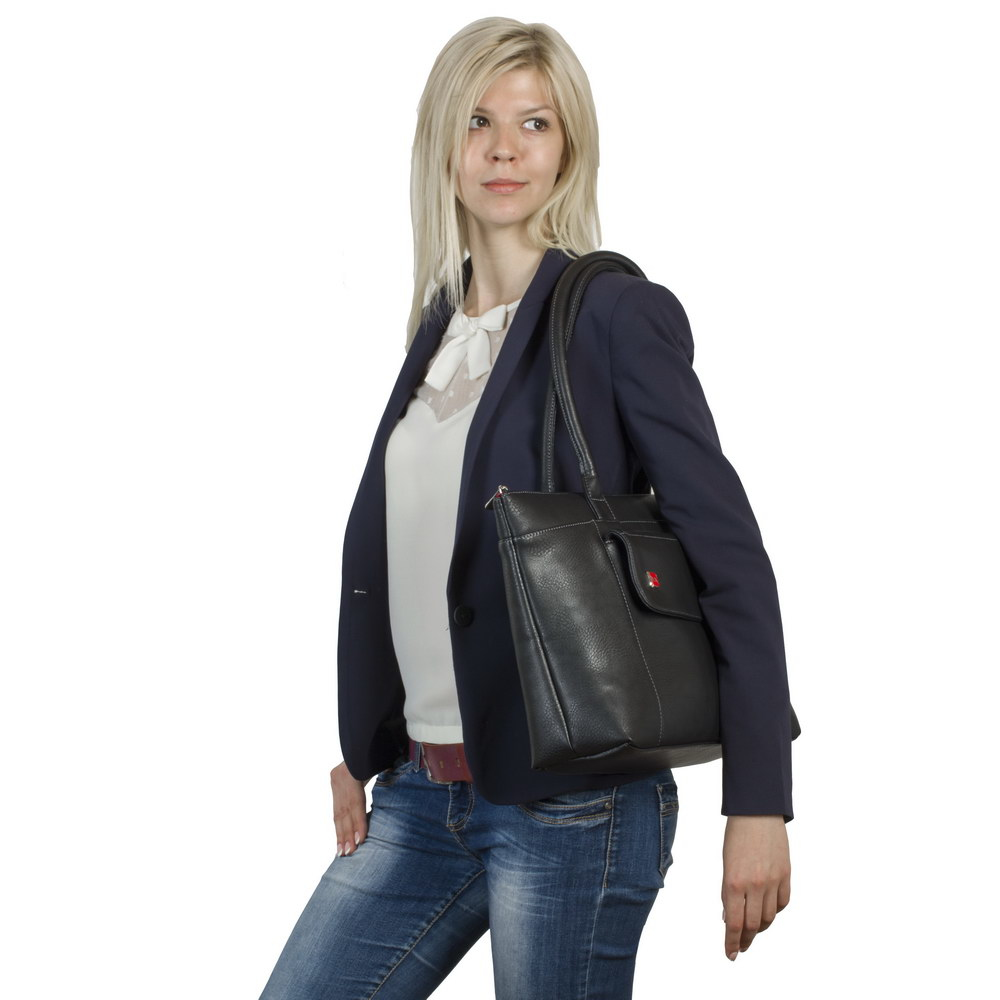 Una donna bionda indossa un blazer blu navy, camicetta bianca e jeans con una borsa nera.