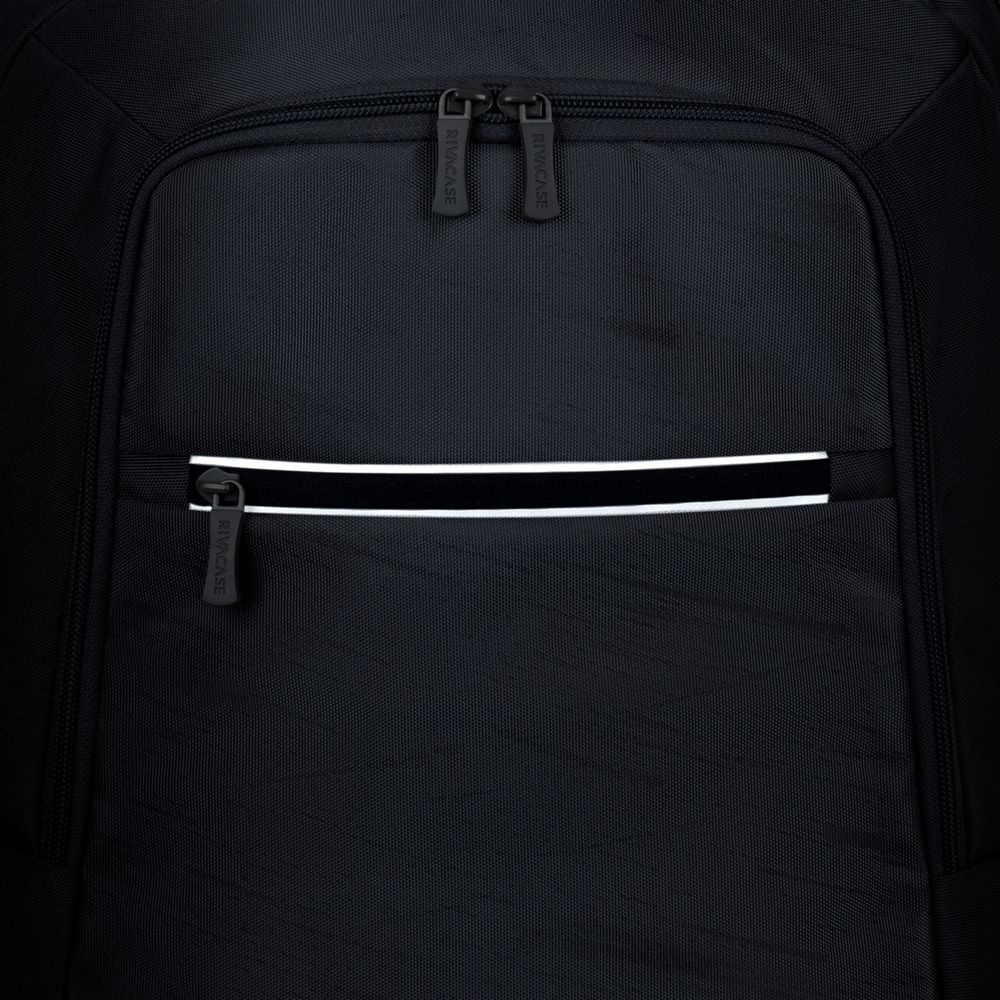Nahaufnahme eines schwarzen Rucksacks mit Reißverschlüssen und einem reflektierenden Streifen.