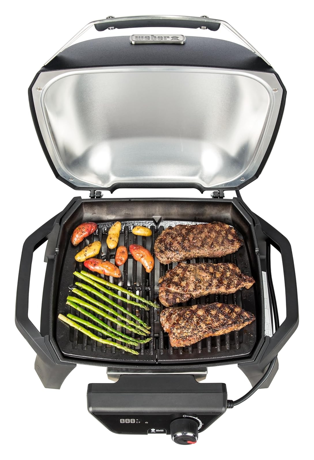 Ein offener Grill mit drei Steaks, Kartoffeln und Spargel auf dem Rost.