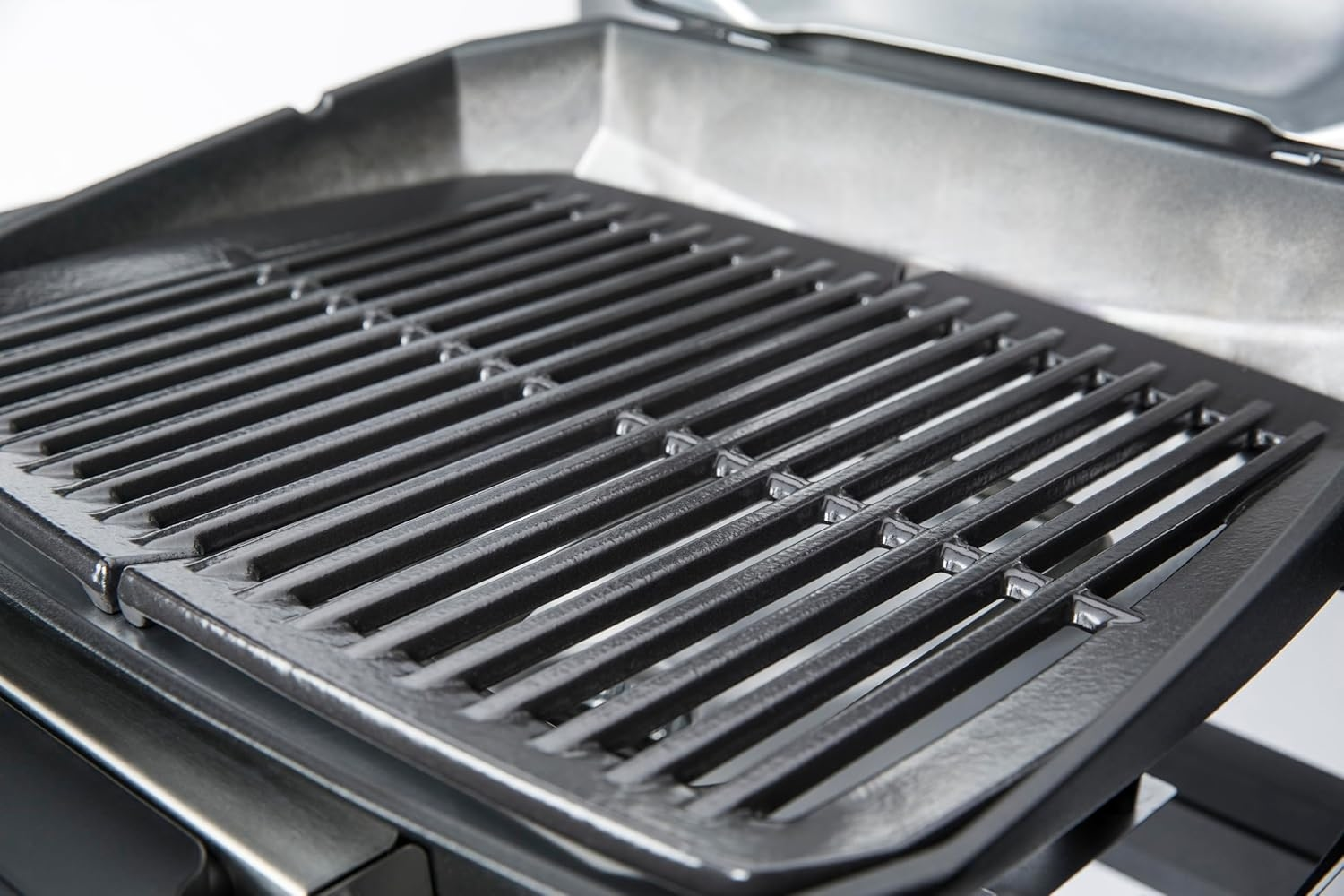 Nahaufnahme eines schwarzen Grillrosts mit parallelen Stäben und metallischem Glanz.