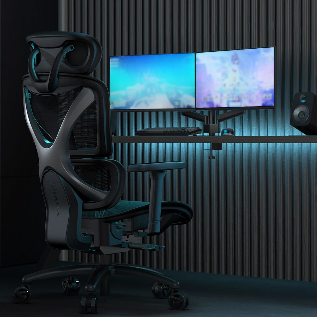 Silla ergonómica para juegos frente a un escritorio con dos monitores, teclado y ratón.