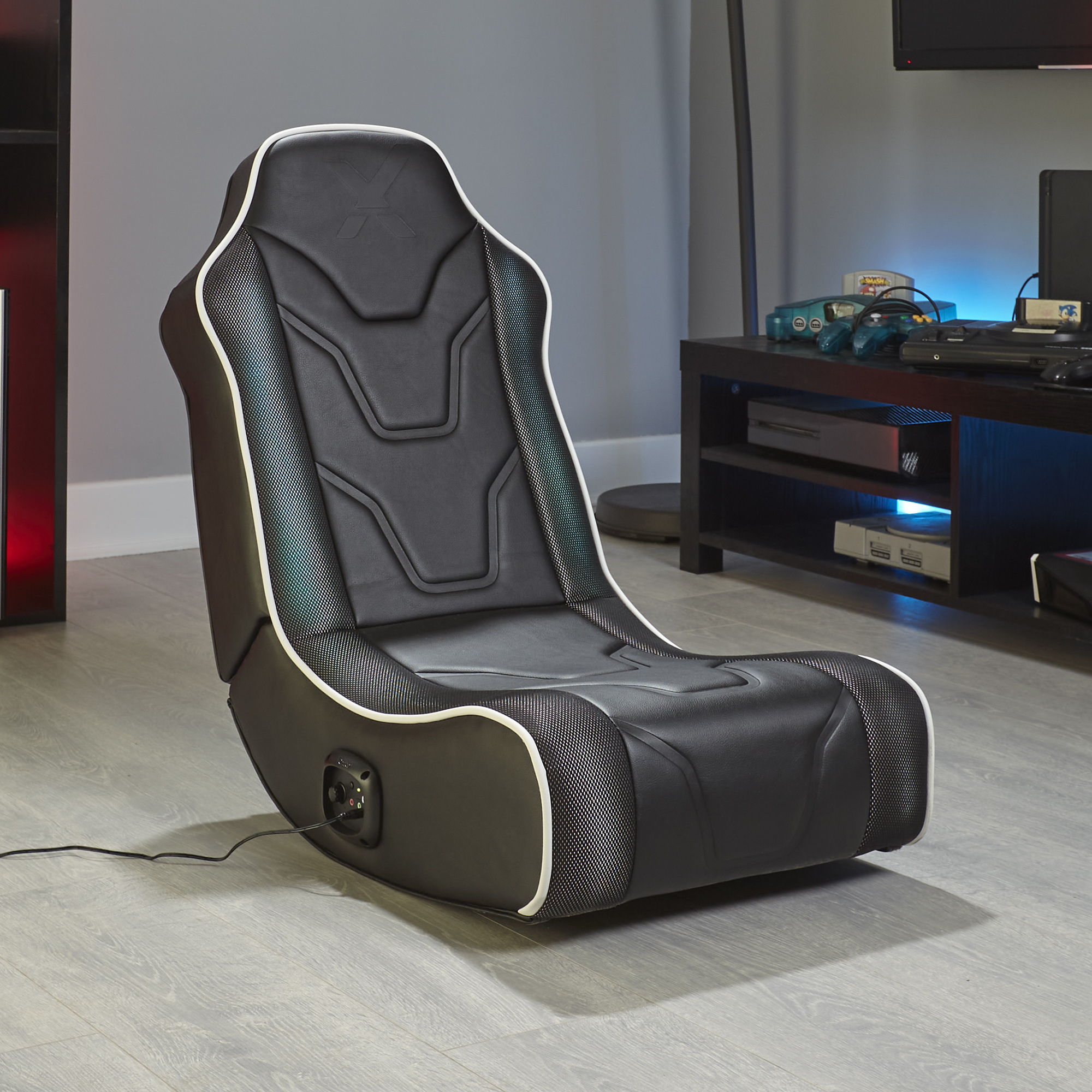 Silla gamer negra con ribete blanco y detalles de malla, cable conectado.
