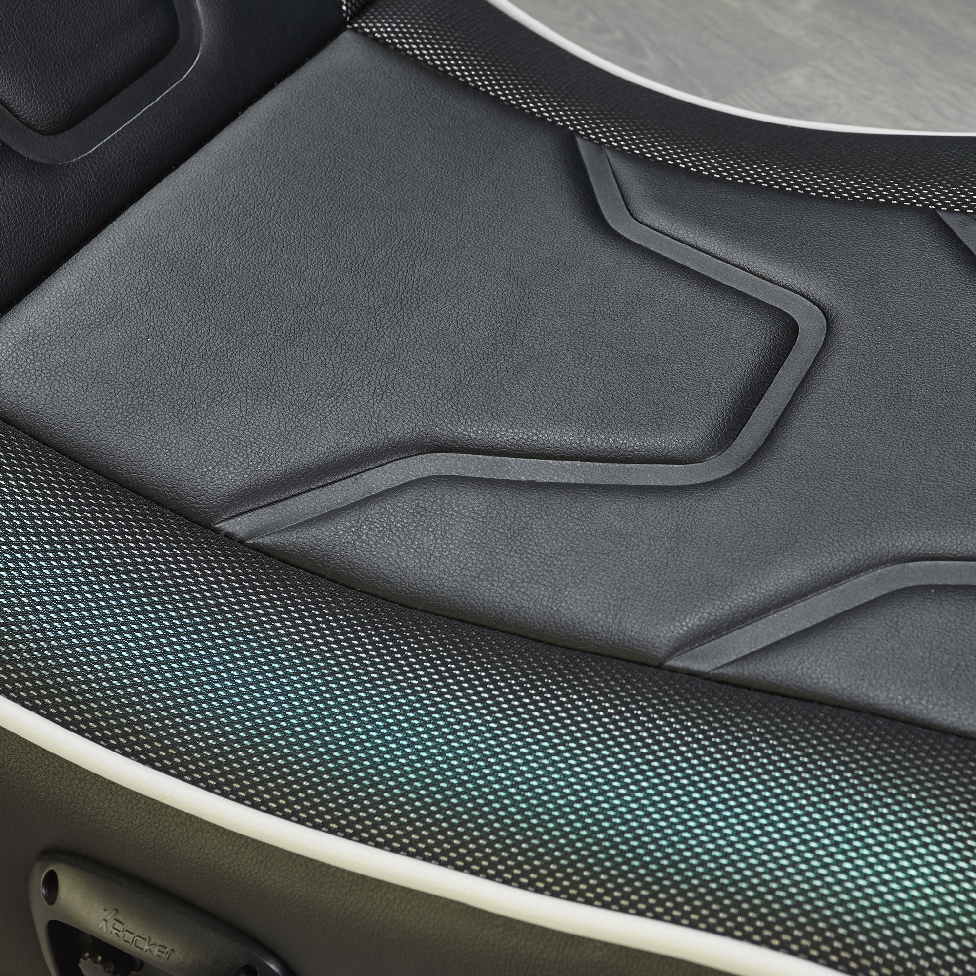 Primer plano de una silla gamer negra con asiento acolchado y detalles de malla.