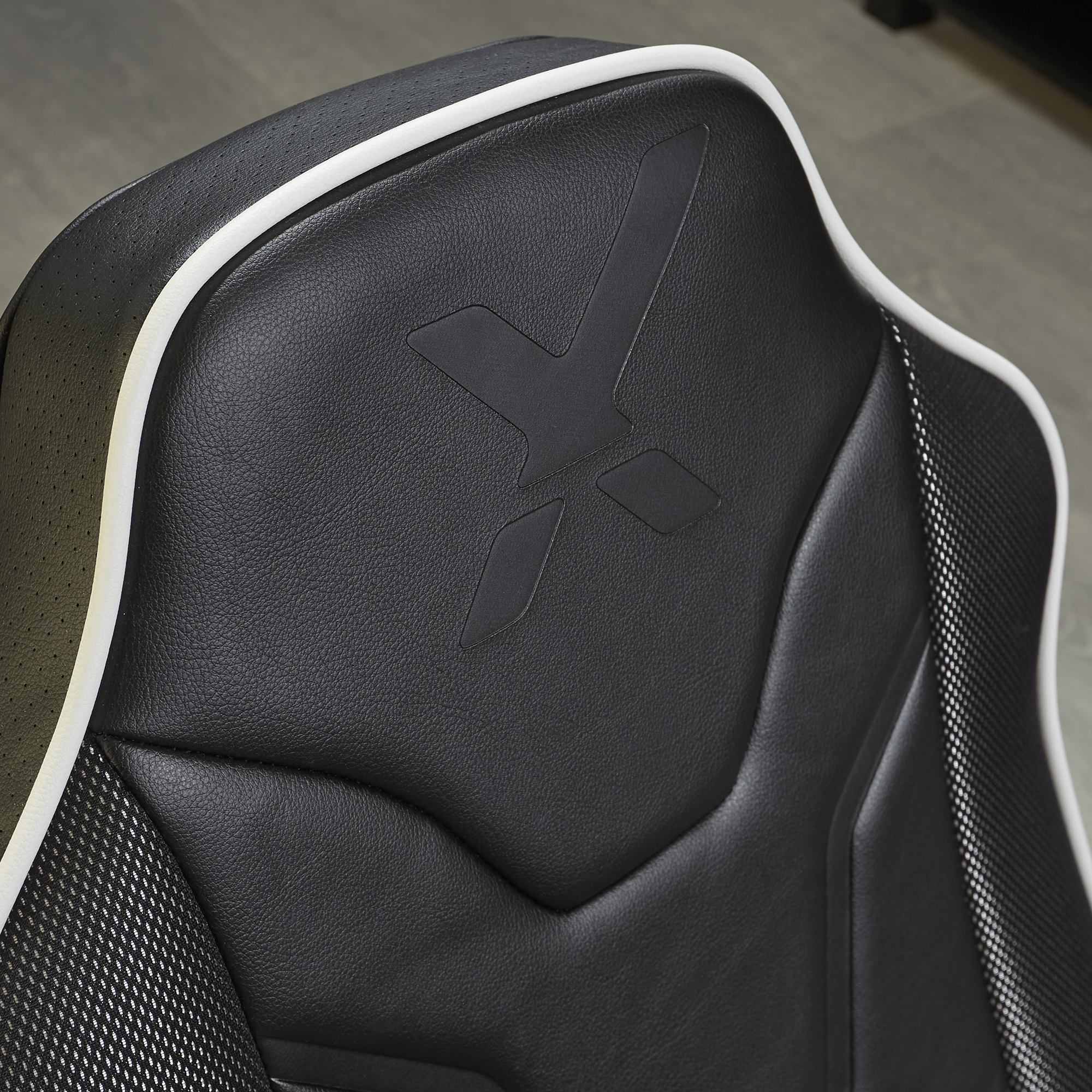 Asiento de coche negro con ribete blanco y logo X en relieve.