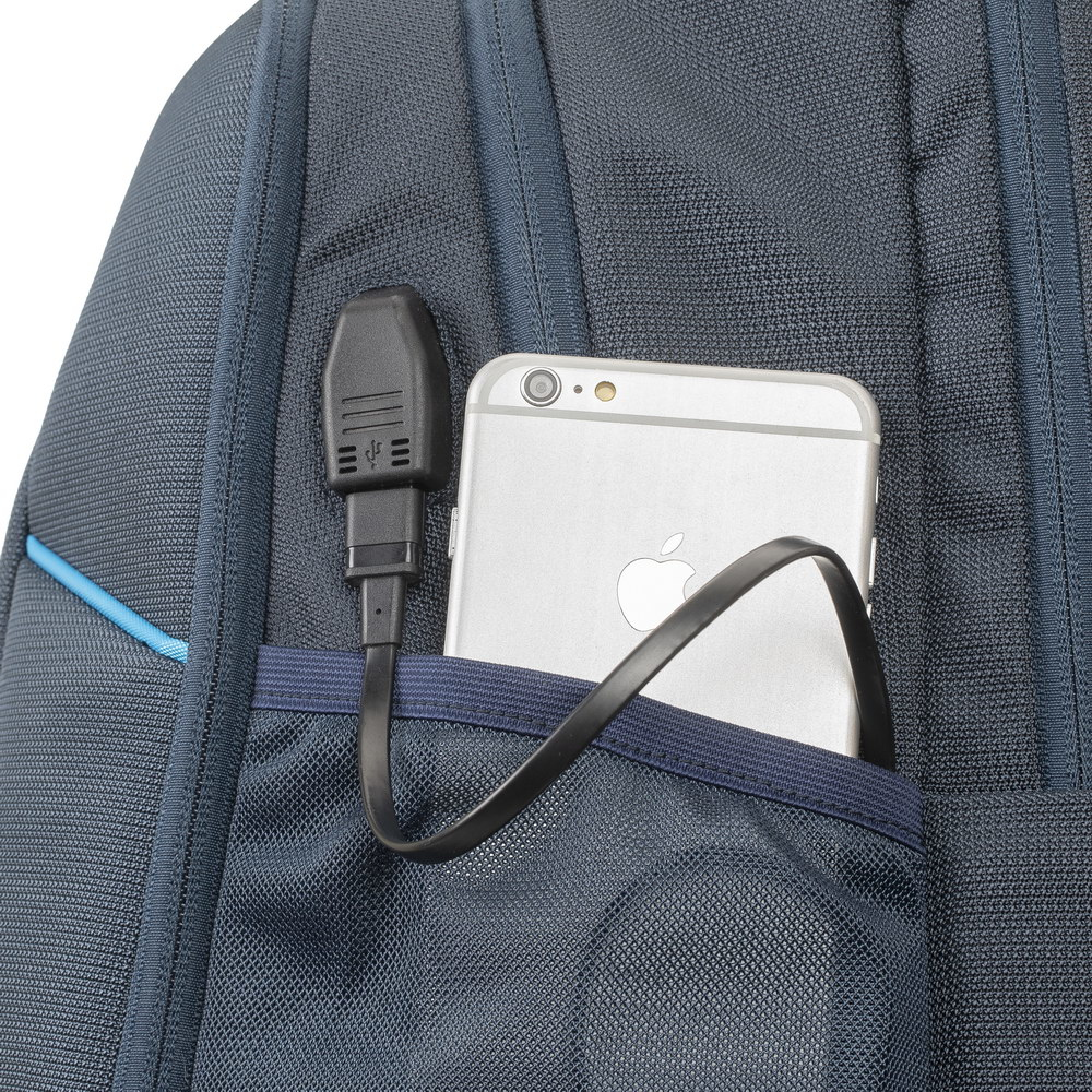 A silver iPhone is in a blue backpack pocket with a black USB cable plugged in.