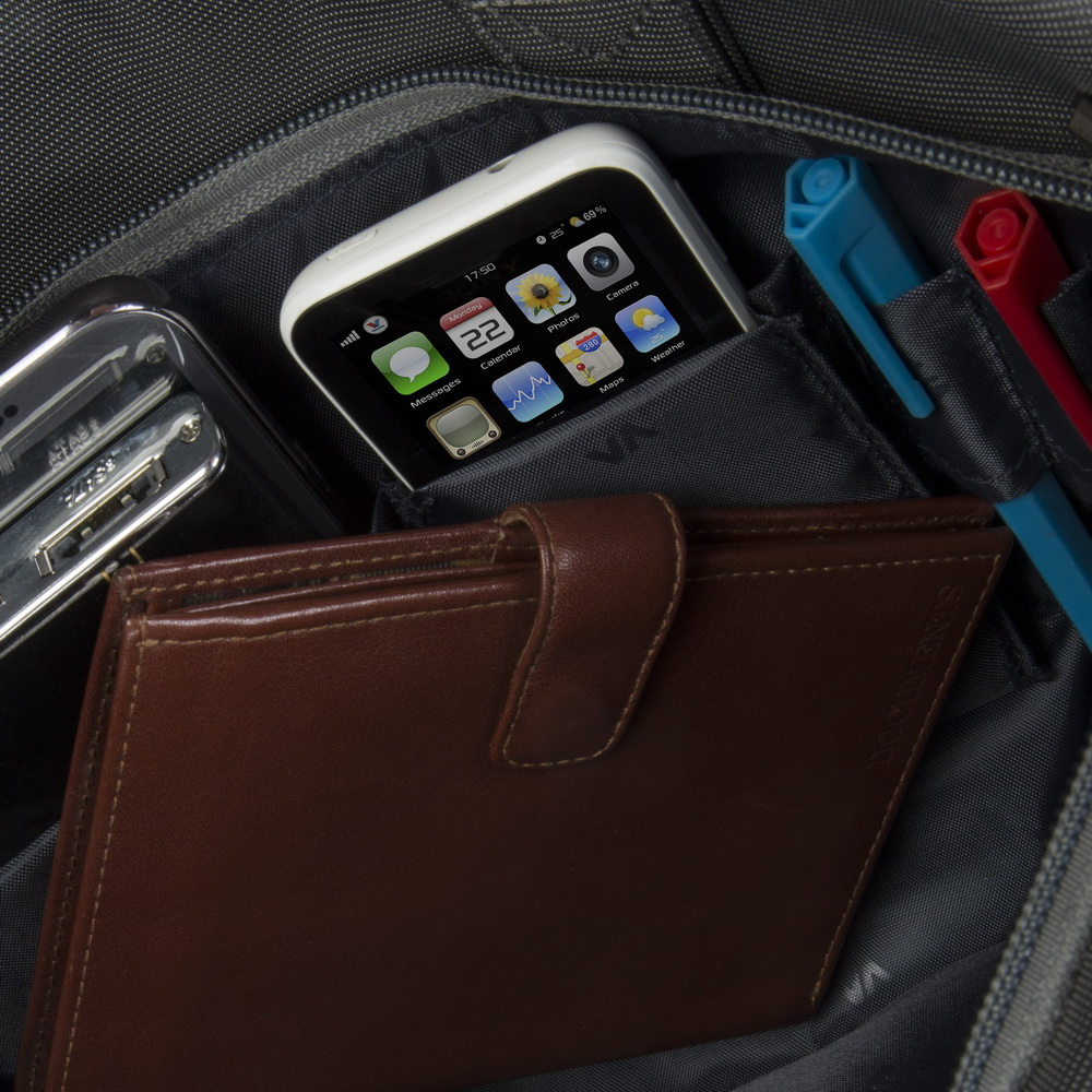 Un portafoglio marrone si trova davanti a uno smartphone e penne in una borsa.