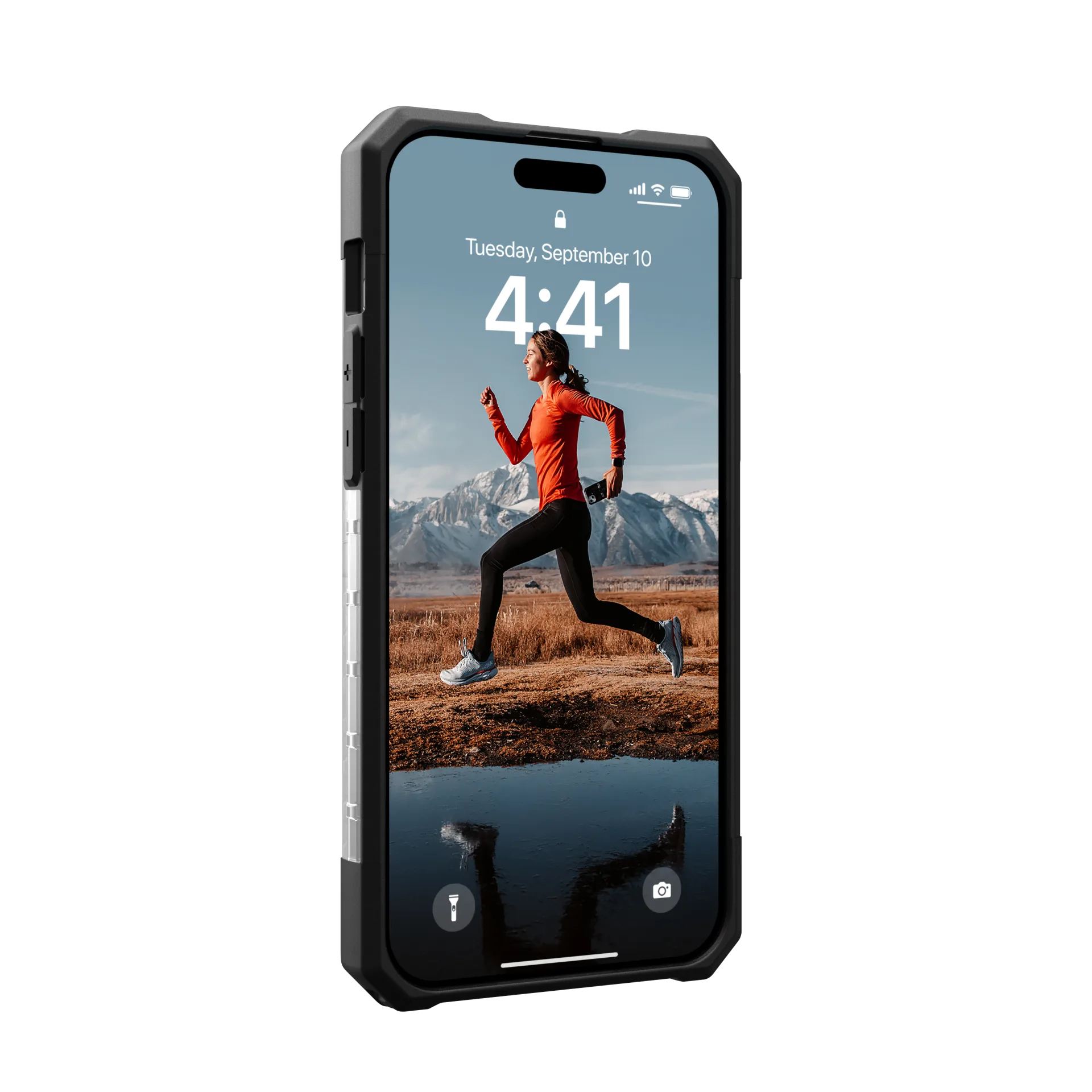 Una donna in arancione corre in un paesaggio montuoso tenendo uno smartphone.