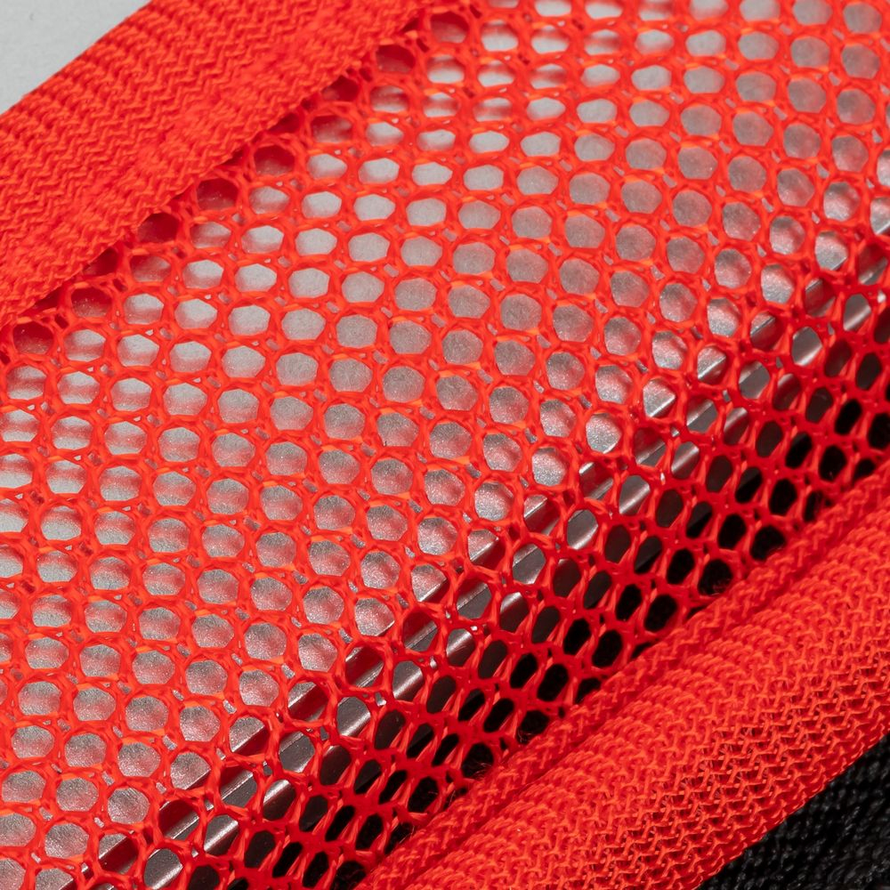 Close-up van een rode mesh stof met een zigzag stofrand.