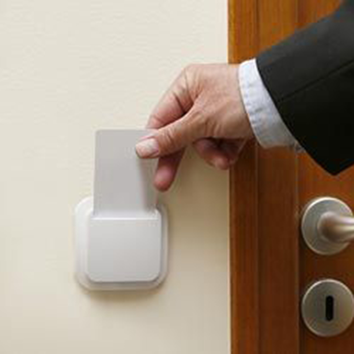 Una mano inserisce una tessera in un lettore accanto a una porta.
