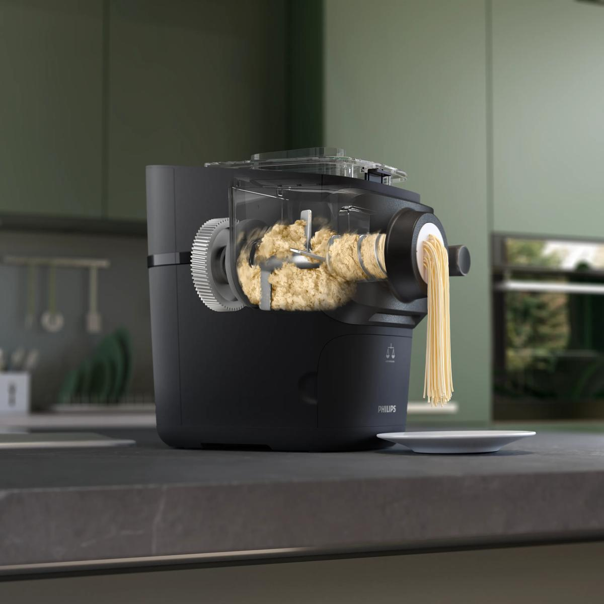 Eine schwarze Nudelmaschine produziert frische Spaghetti auf einer Arbeitsplatte.