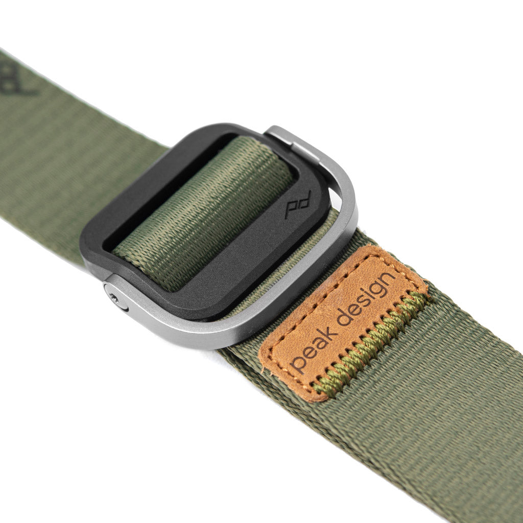 Cinghia verde con fibbia nera e argento. Etichetta in pelle 'peak design'.