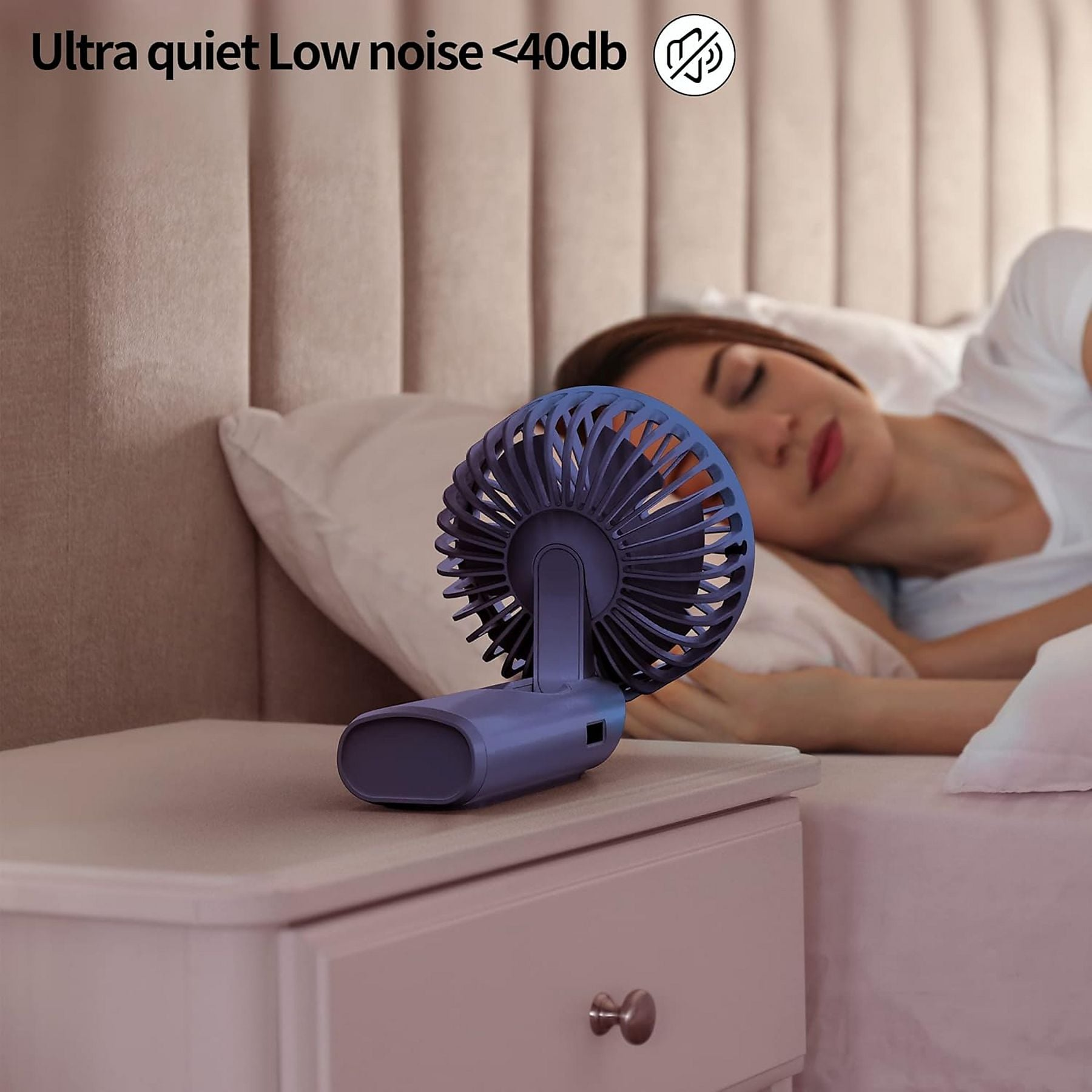 Ein kleiner blauer Ventilator steht auf einem Nachttisch neben einer schlafenden Frau.