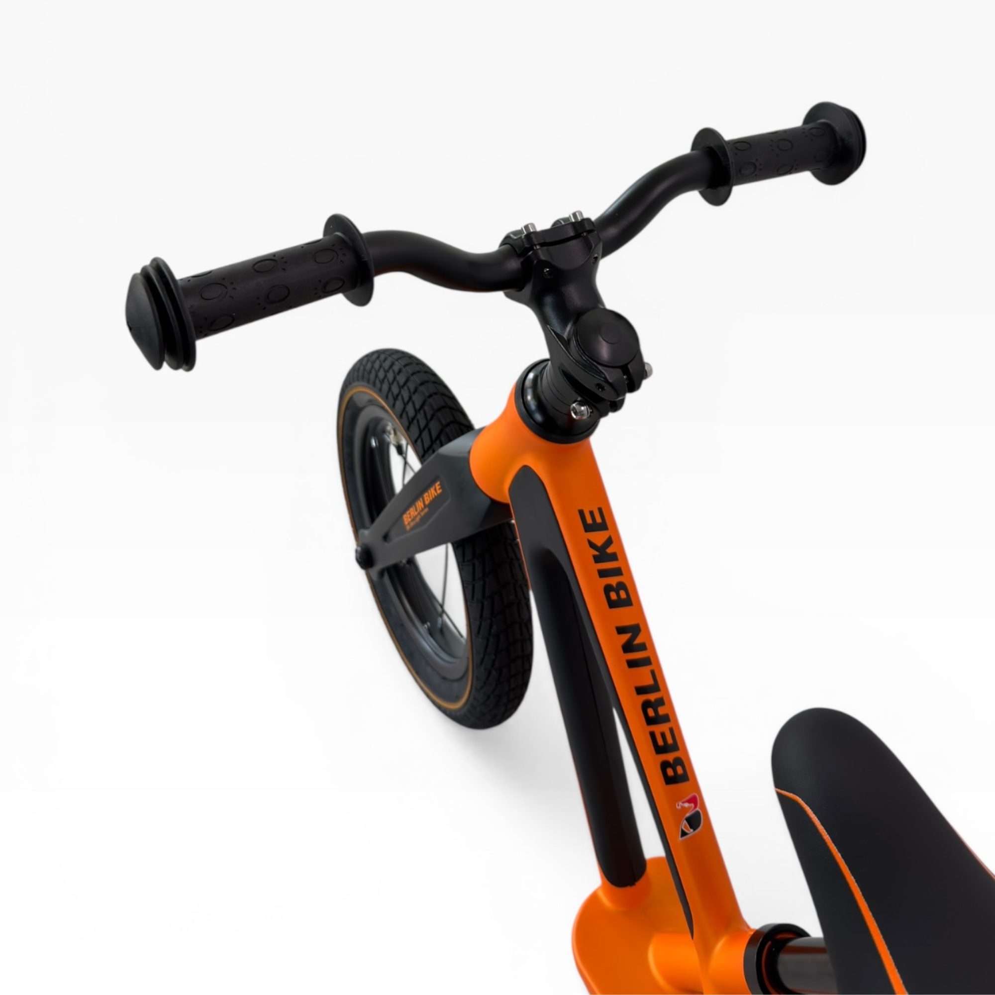 Ein orangefarbenes Laufrad mit schwarzen Griffen und Rädern auf weißem Hintergrund.