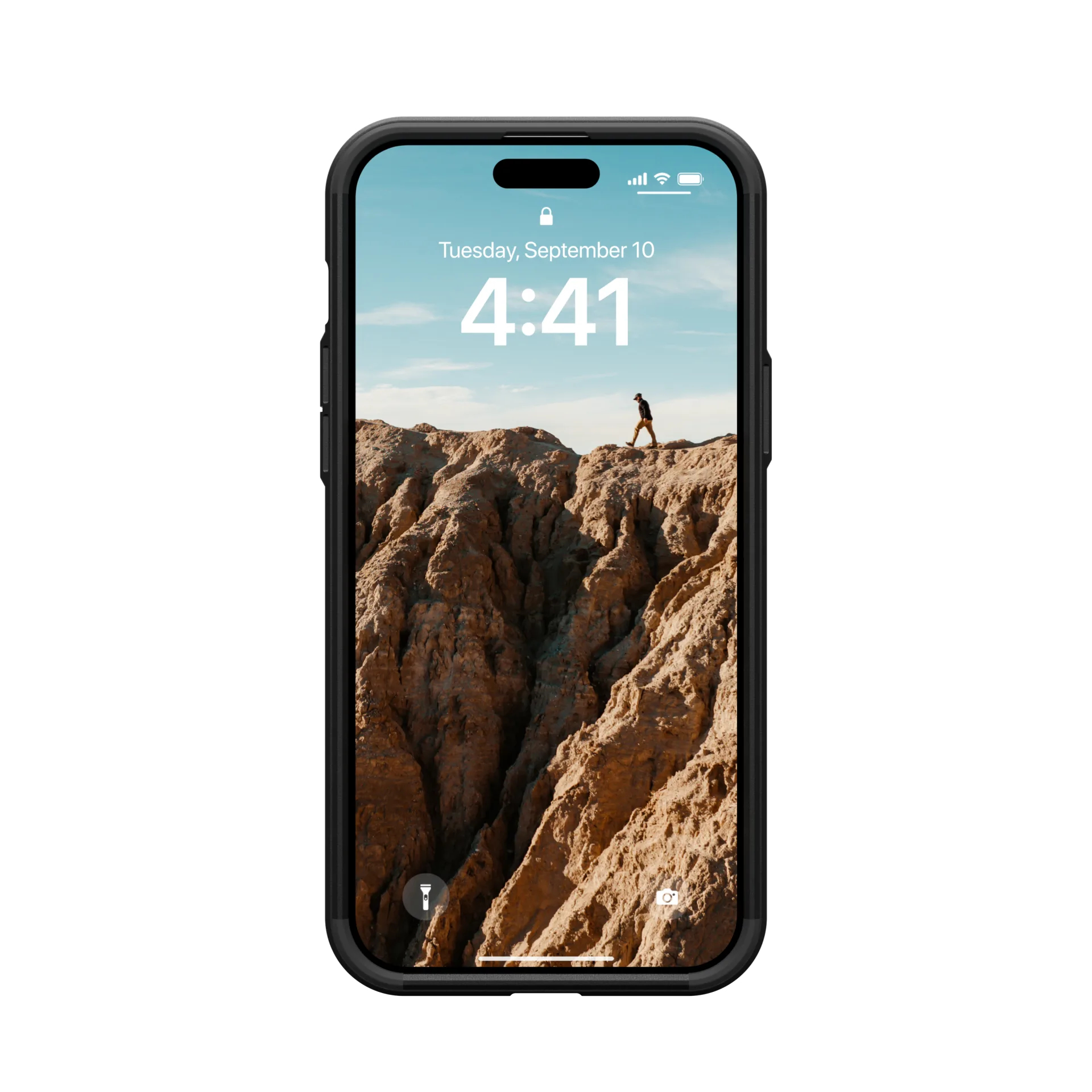 La pantalla del iPhone muestra a un hombre haciendo senderismo en una montaña desértica bajo un cielo azul.