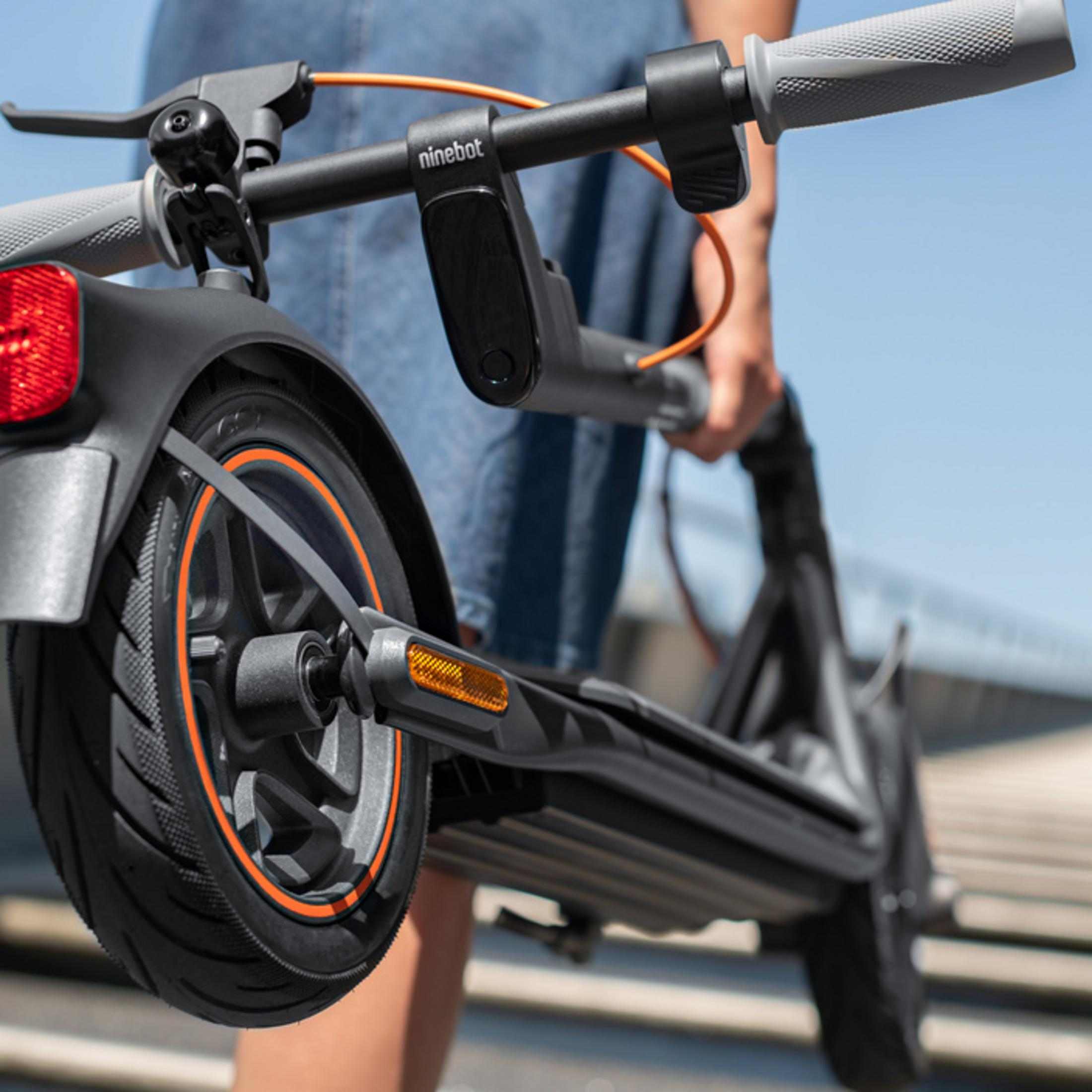 Grauer Roller mit orangen Akzenten, von Person im Jeanshemd getragen.