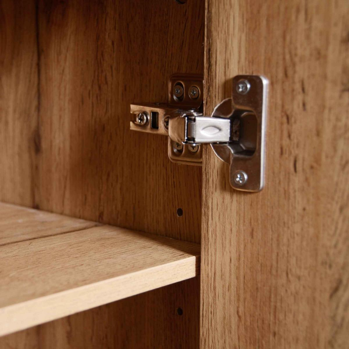 Ein silberner Scharnierbeschlag ist an einem Holzschrank befestigt. Eine Holzablage ist links zu sehen.