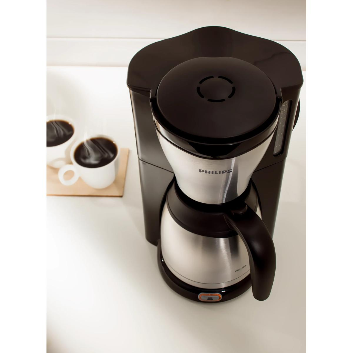Macchina da caffè Philips nera con caraffa termica e due tazze di caffè.