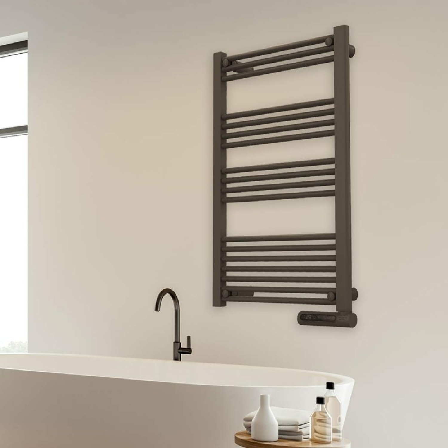Toallero radiador gris oscuro sobre una bañera blanca con grifo negro.