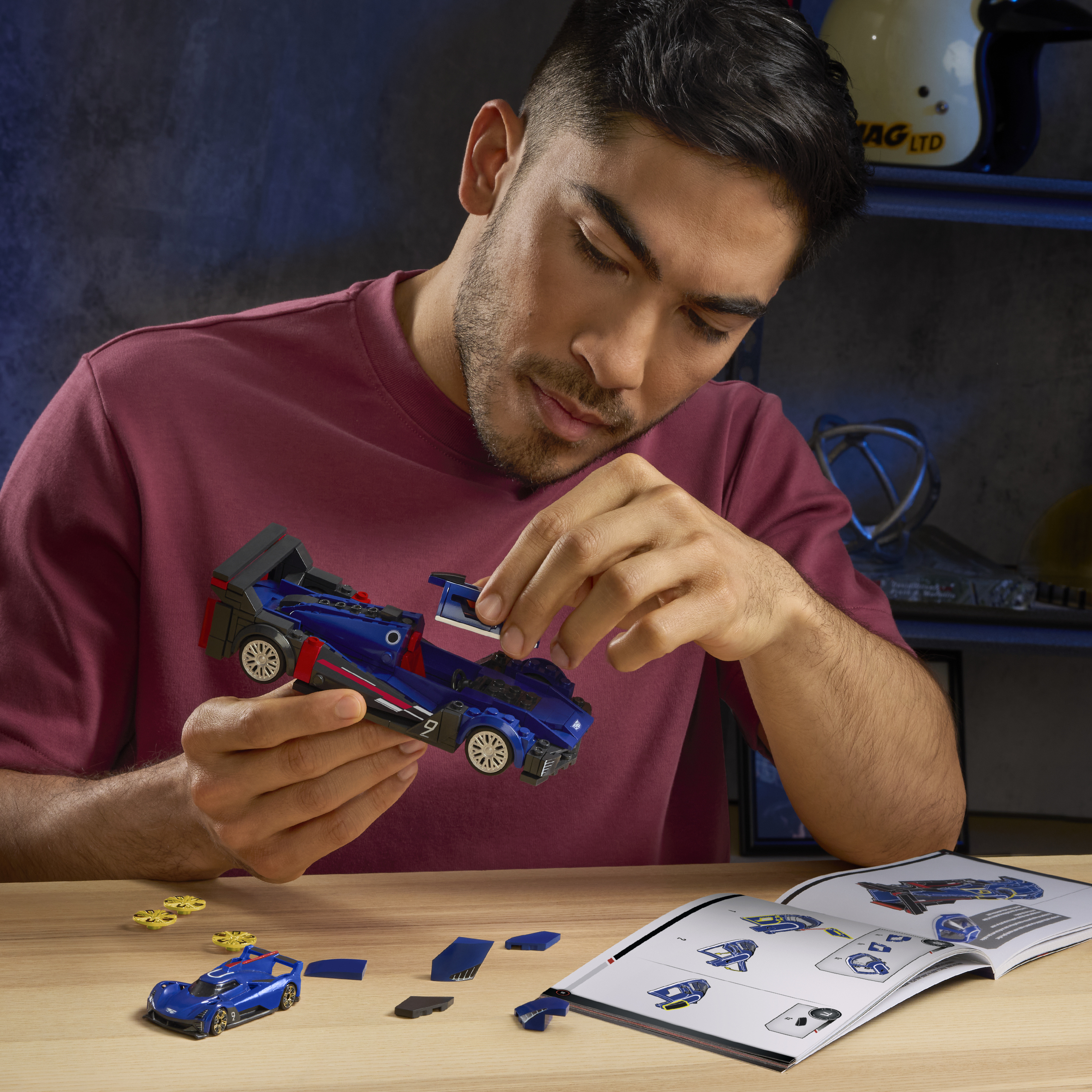 Uomo che costruisce un'auto da corsa giocattolo blu con istruzioni.