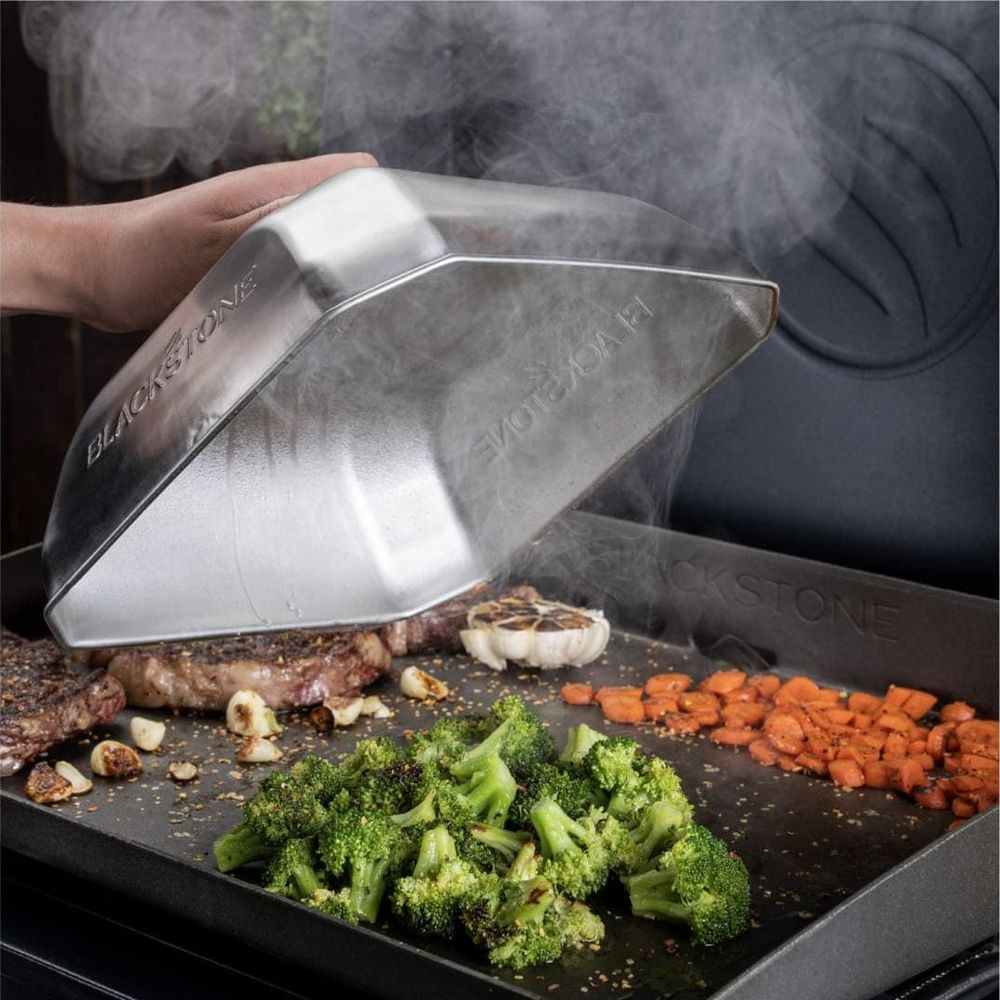 Des steaks, du brocoli, des carottes et de l'ail sont cuits à la vapeur sur une plaque.