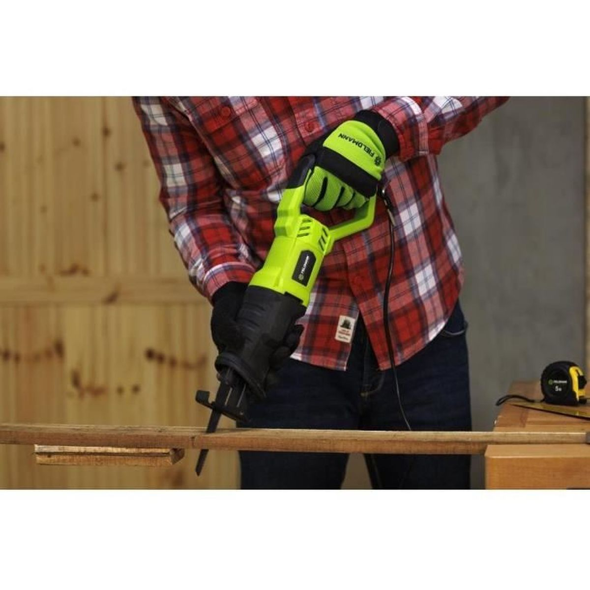 Osoba w rękawiczkach używa piły szablasty do cięcia drewna.