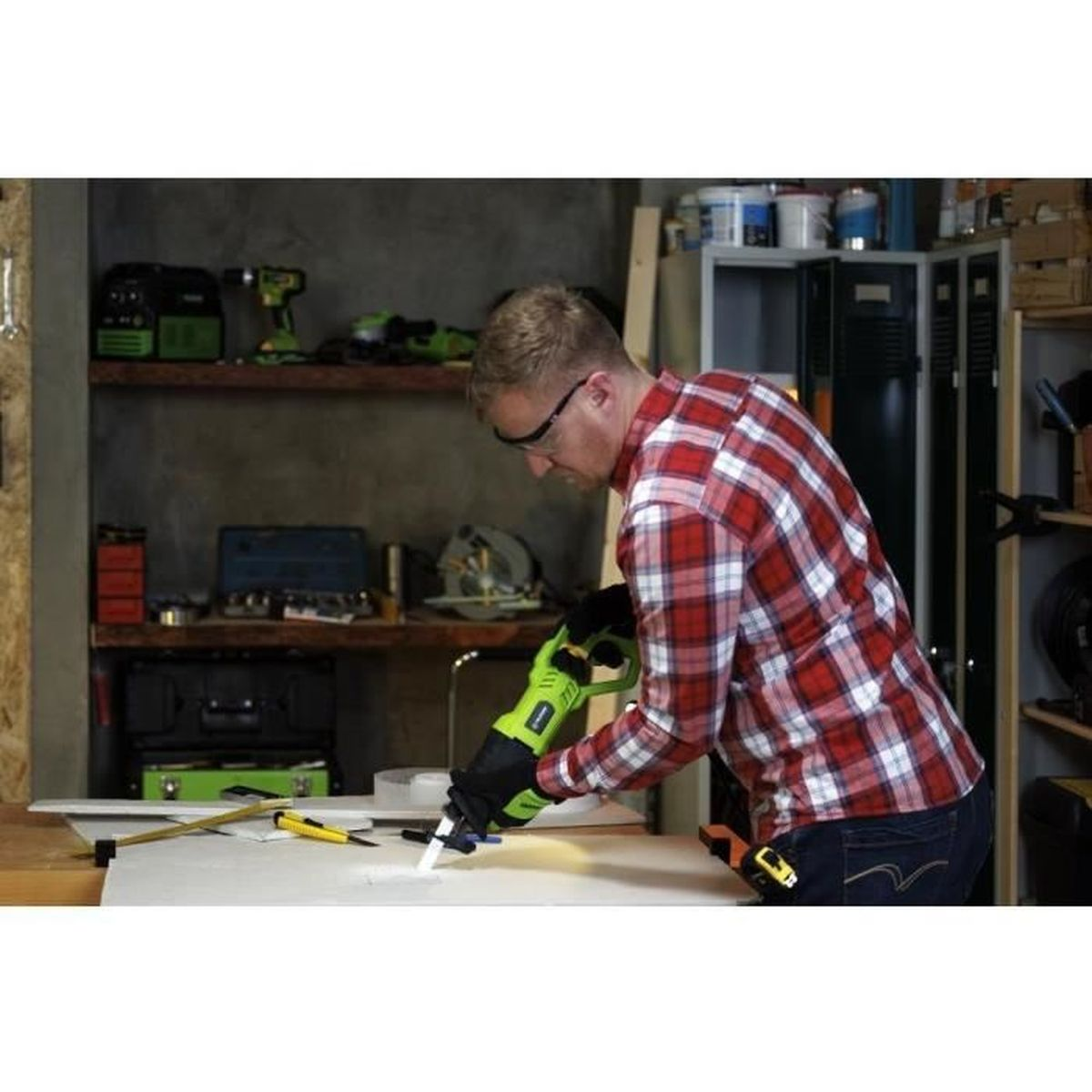 Mężczyzna z piłą szablastą pracuje przy drewnie w warsztacie z narzędziami.