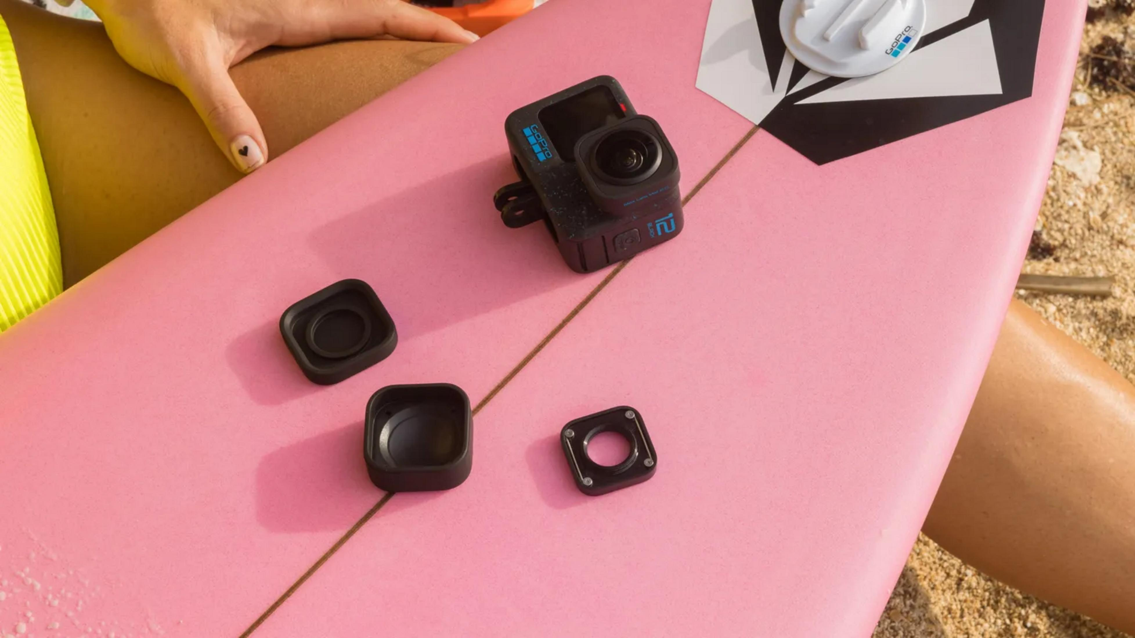 Eine Person auf einem Surfbrett mit einer GoPro-Kamera und Zubehör auf Sand.