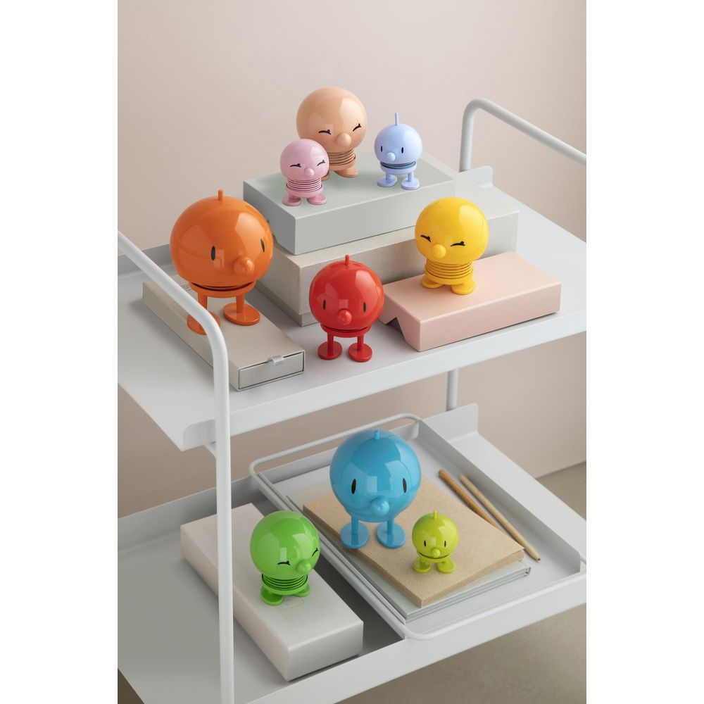 Varie figure colorate su uno scaffale bianco, ad es. arancione, rosso, giallo, blu, rosa, beige, verde.