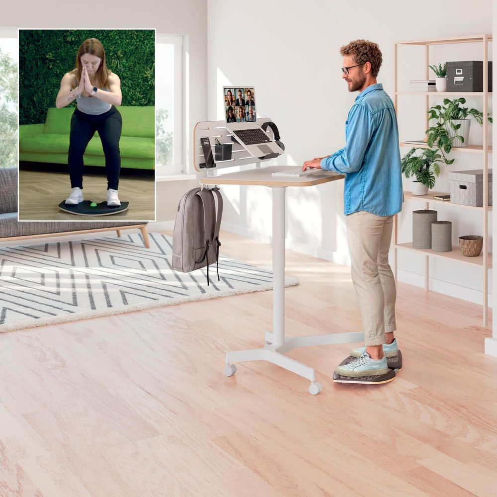 Mann am Stehtisch, Frau macht Kniebeugen auf Balance Board.