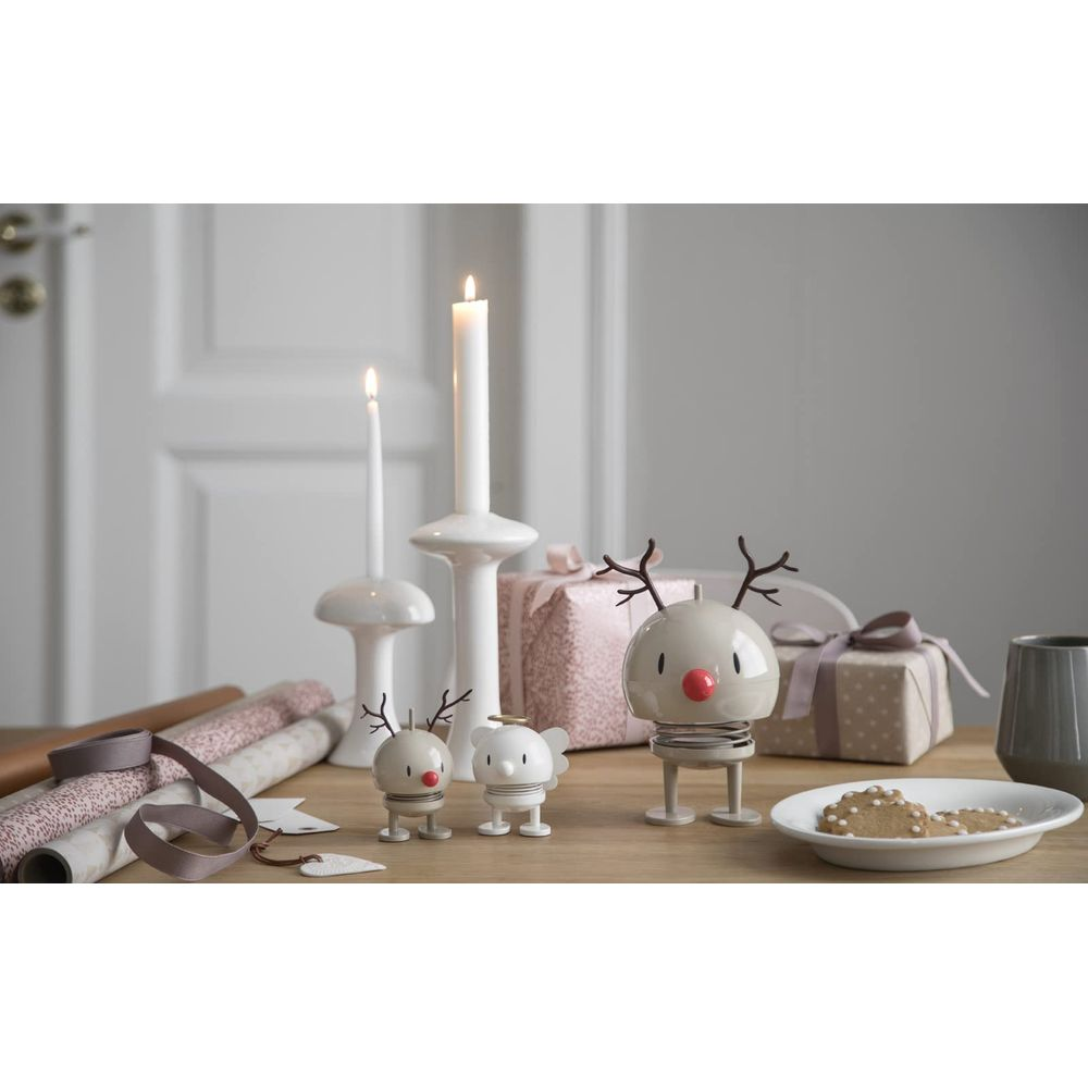 Decorazioni natalizie: candelabri, regali, statuette di renne e biscotti su tavolo legno.