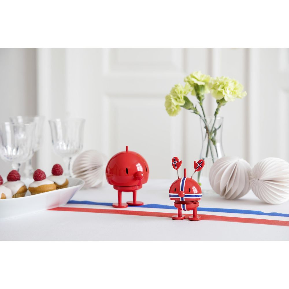 Due figure rosse con bandiere norvegesi e cupcake su un tavolo.